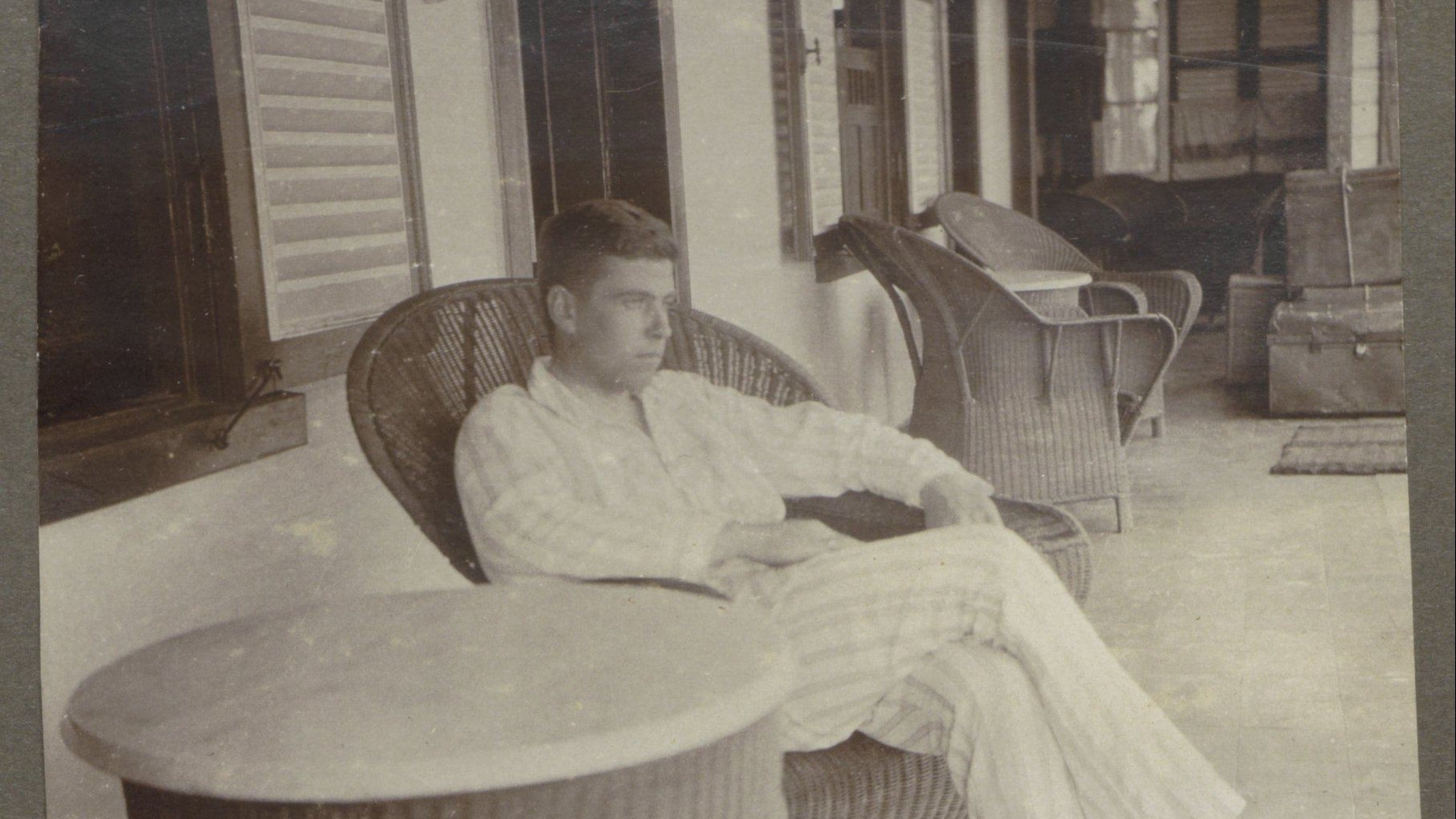 Homme en pyjama assis dans un fauteuil en osier sur une véranda entre 1920 et 1930 Image