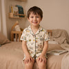 Petit garçon souriant en pyjama, assis sur son lit