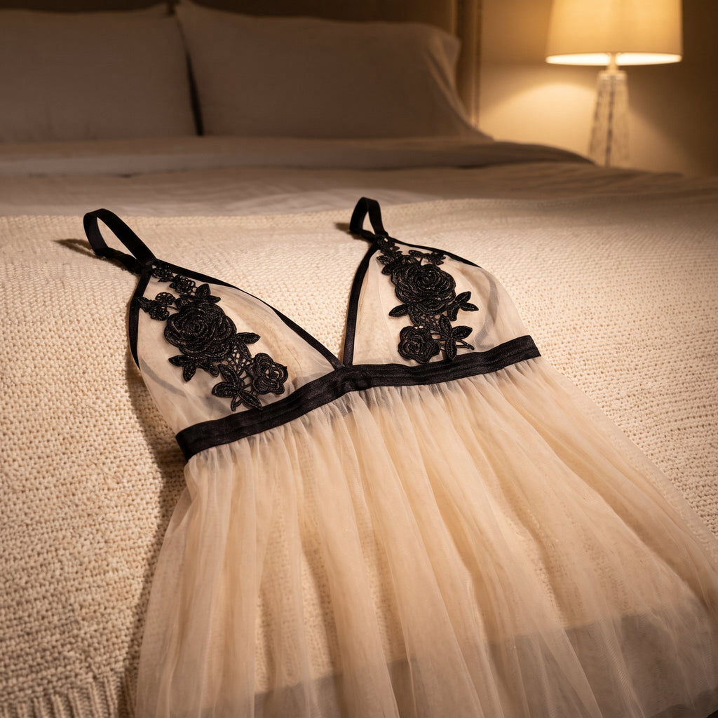 La nuisette étalée sur un lit, ses deux bonnets et leurs roses en haut du cadre, sa jupe ouverte en éventail, sous la lumière basse d’une lampe de chevet allumée un soir