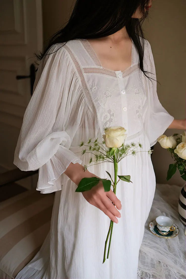 Plastron brodé et encolure carrée de la chemise de nuit blanche, avec une tasse de thé Image
