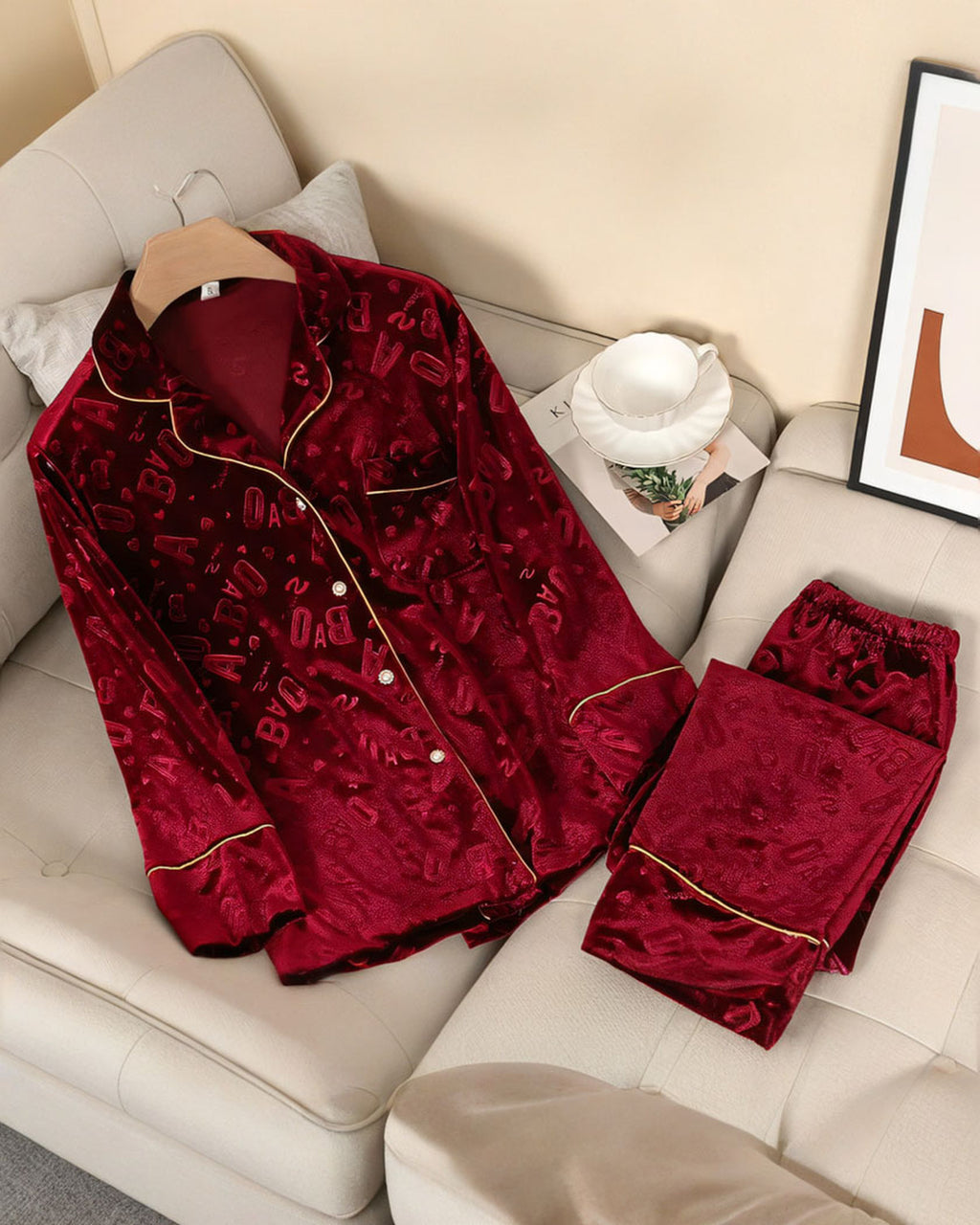 Ensemble de pyjama en velours rouge à lettres en relief, chemise et pantalon posés sur un canapé crème