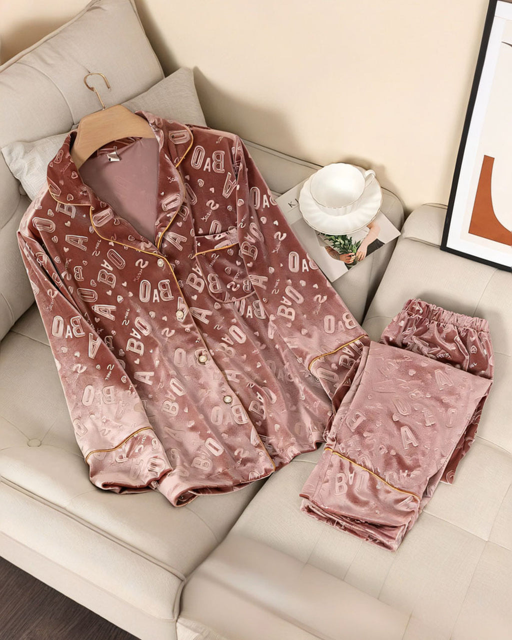Ensemble de pyjama en velours rose à lettres en relief, chemise et pantalon posés sur un canapé crème
