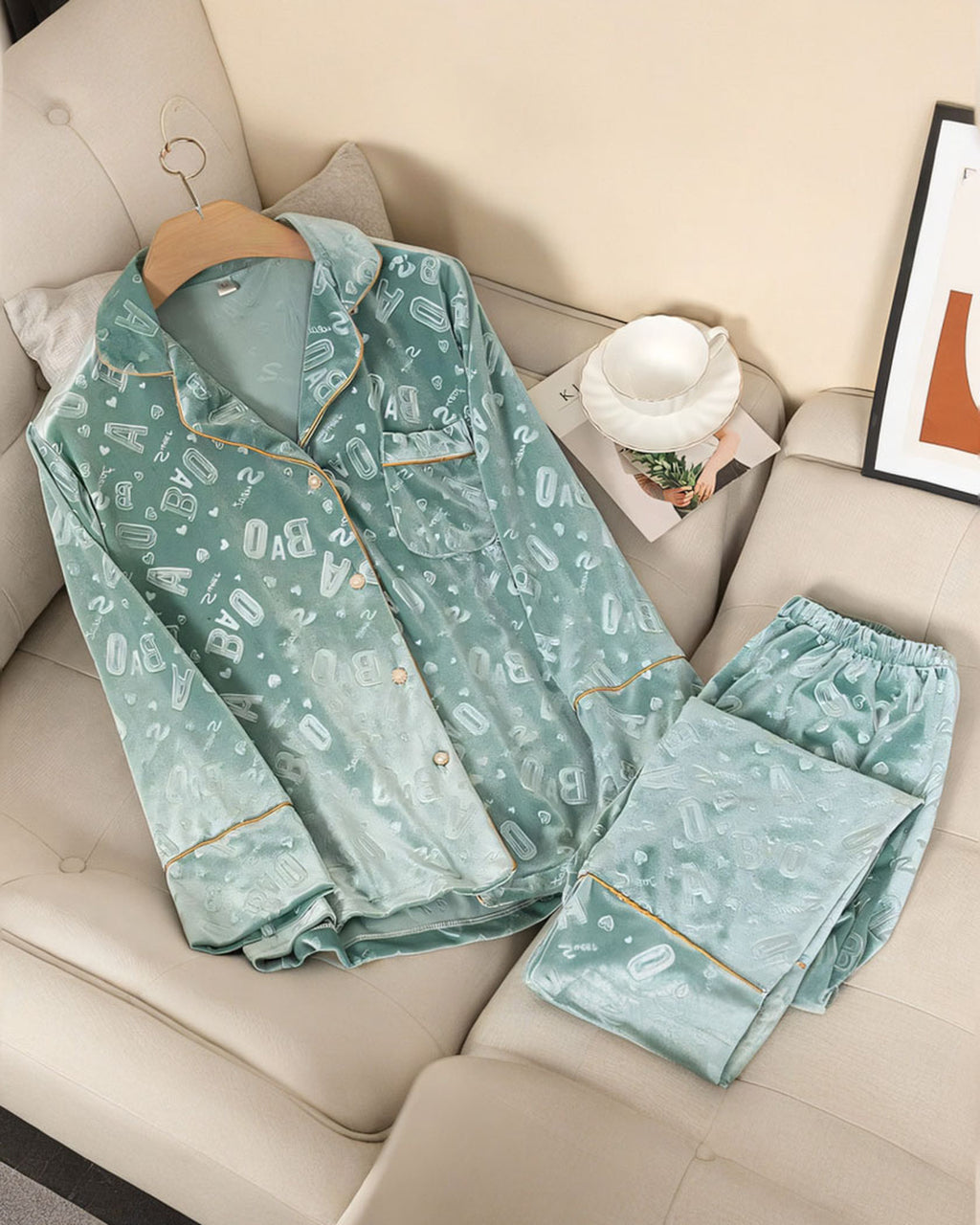 Ensemble de pyjama en velours vert d'eau à lettres en relief, chemise et pantalon posés sur un canapé crème