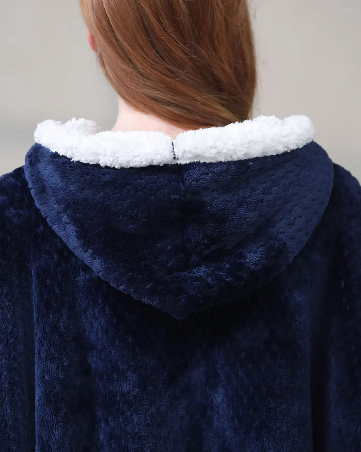 Capuche d'un peignoir de maternité bleu marine vue de dos, sa bordure de fausse fourrure blanche faisant le tour de l'ouverture