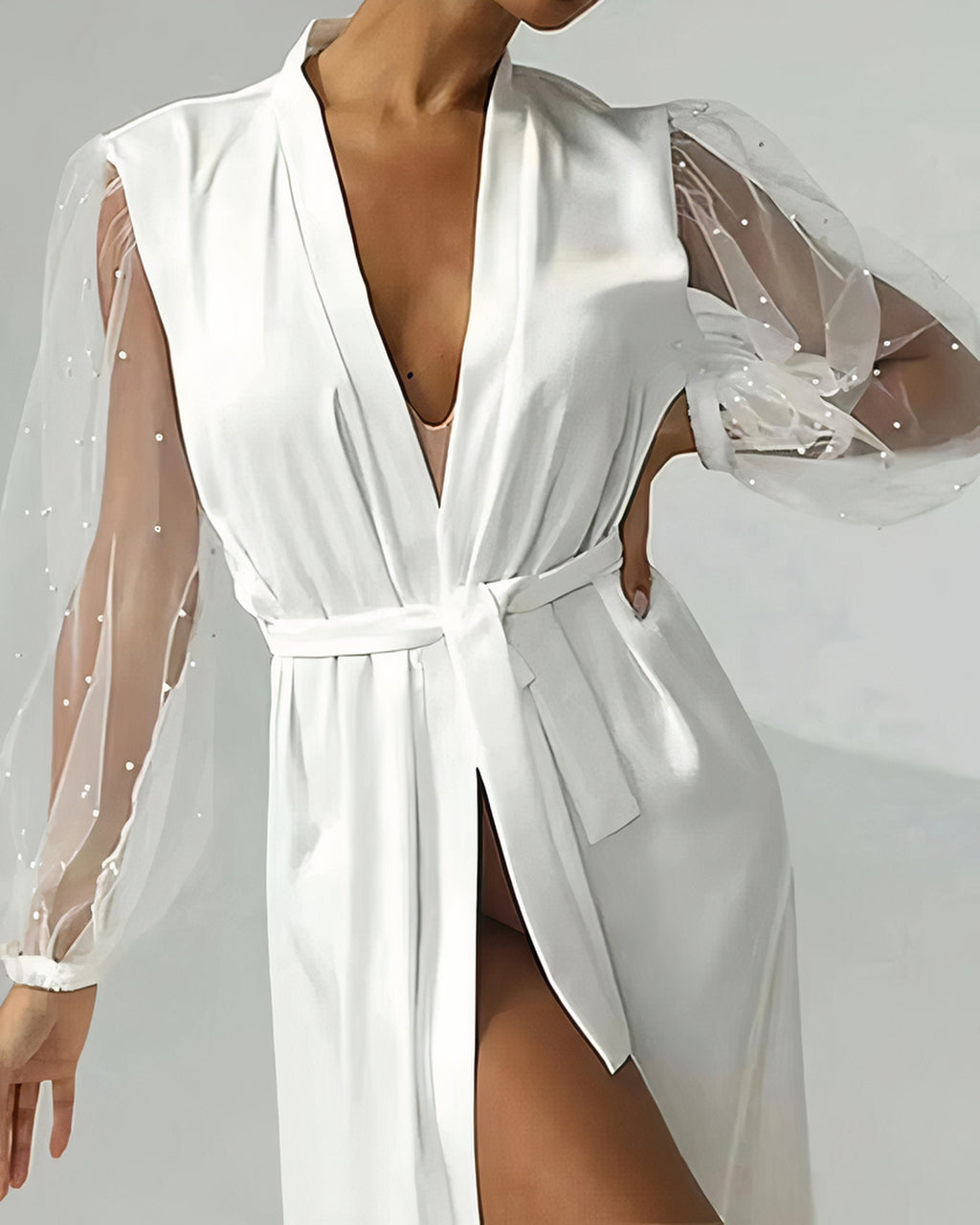 Ceinture en satin nouée à la taille et manche en voile perlé du peignoir de mariée blanc, vue de près