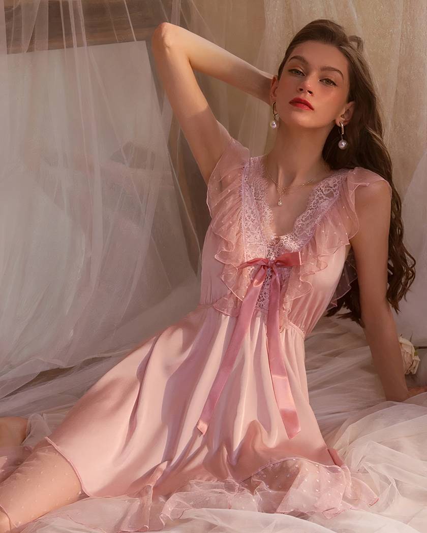 Chemise de nuit courte en satin rose poudré portée assise, volants de tulle