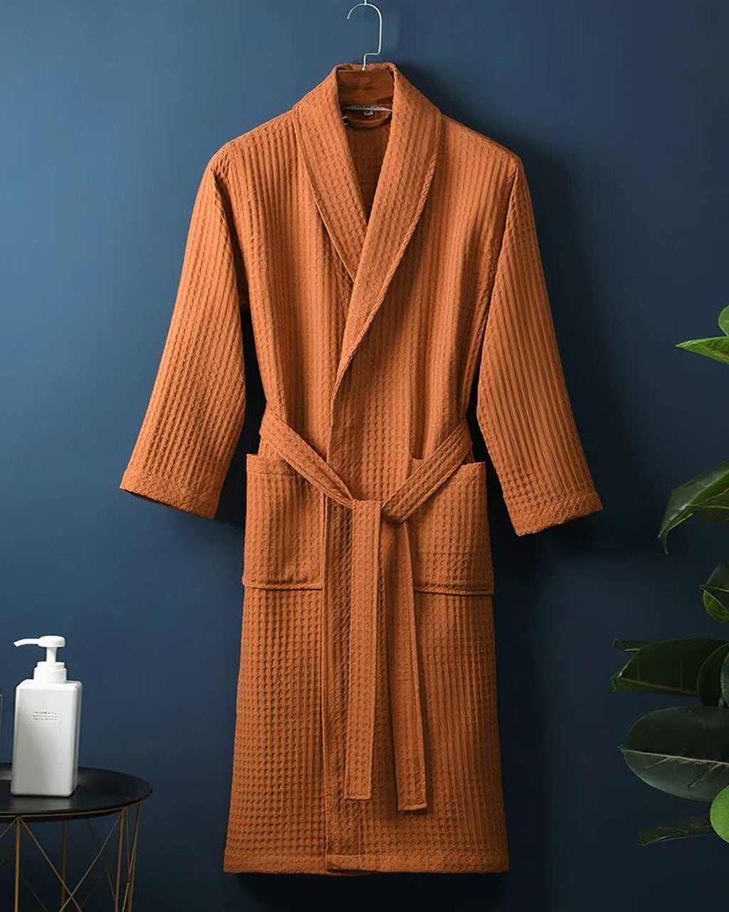 Le coloris orange terracotta présenté sur un cintre, du col jusqu’à l’ourlet droit, le gaufrage en petits carrés visible sur toute la pièce