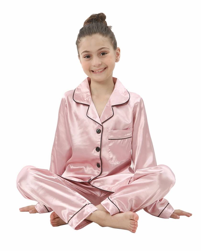 Pyjama fille en satin rose porté assis, chemise boutonnée et pantalon long
