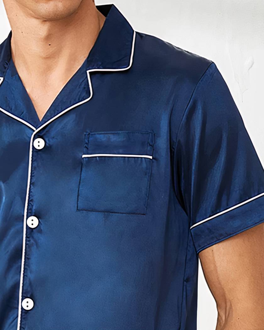 Gros plan du col ouvert à revers et de la poche poitrine à passepoil blanc, satin bleu marine