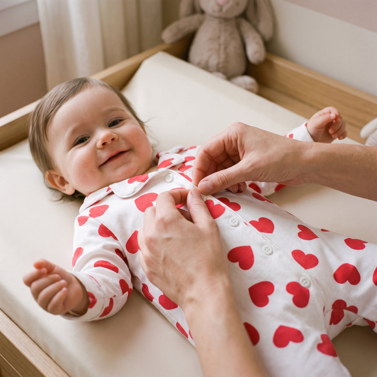 Un parent reboutonne la barboteuse de son bebe sur la table a langer Image