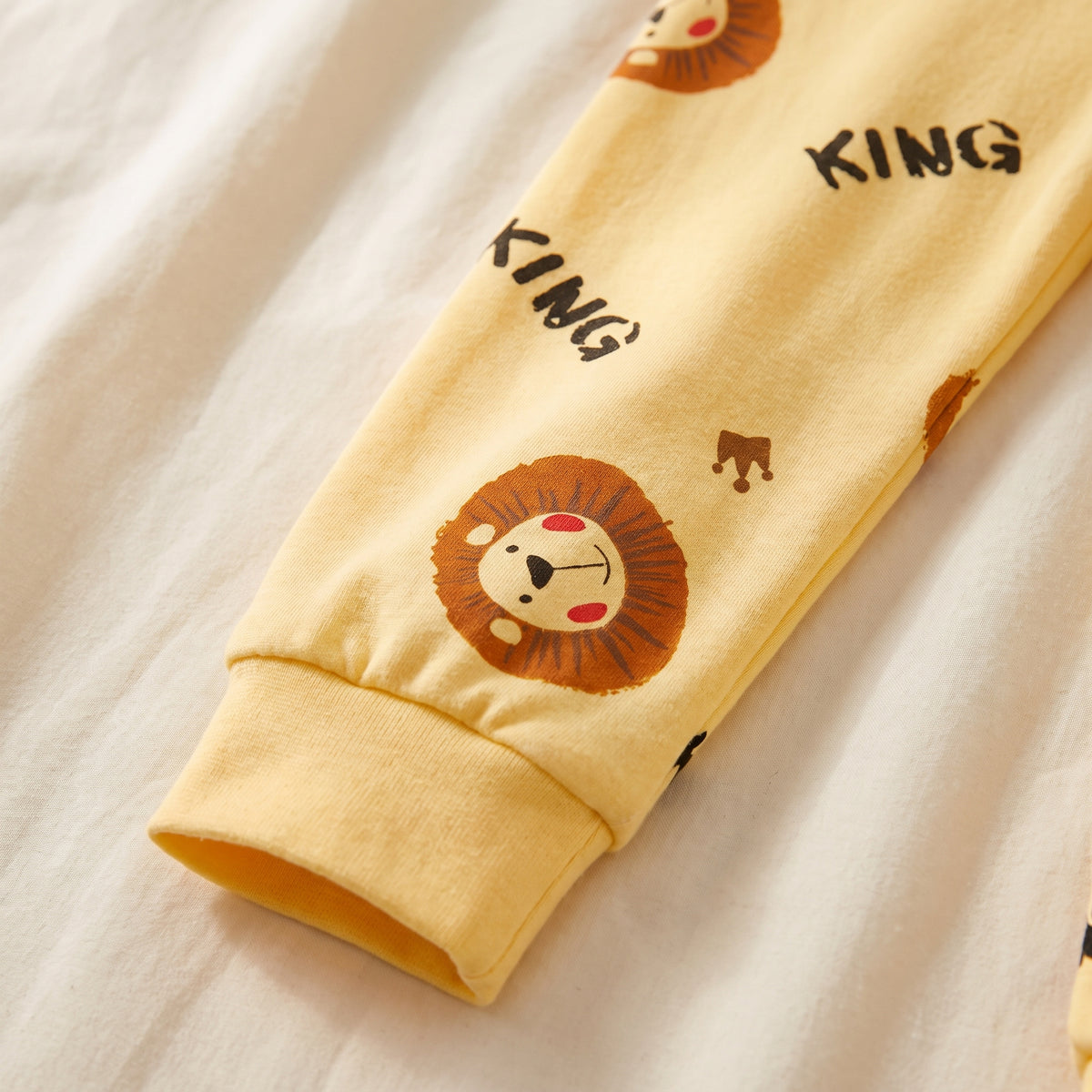 Une jambe du bas de pyjama garçon, semée de petits lions et de couronnes
