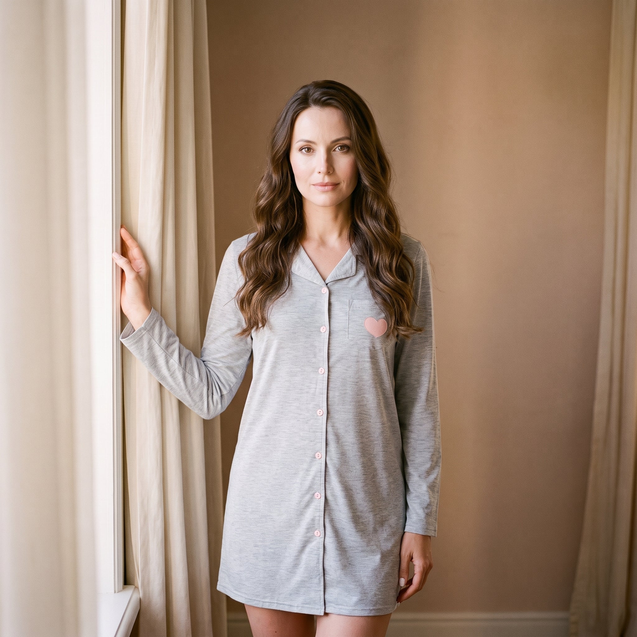Femme portant la chemise de nuit femme grise boutonnée près d'une fenêtre Image