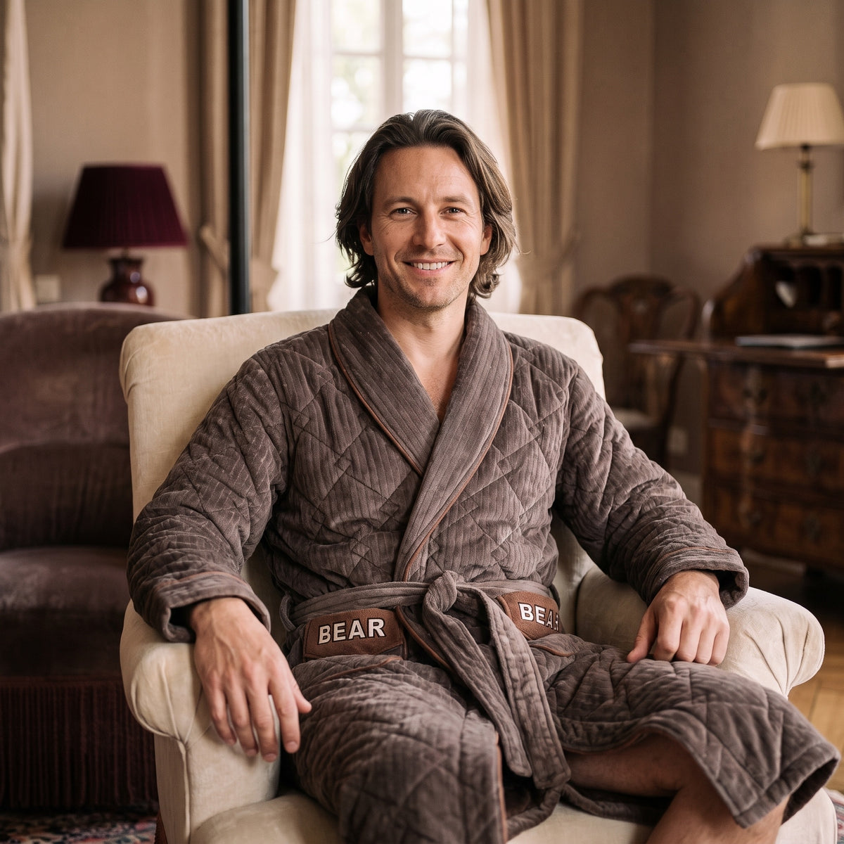Homme souriant assis avec le peignoir polaire marron matelassé