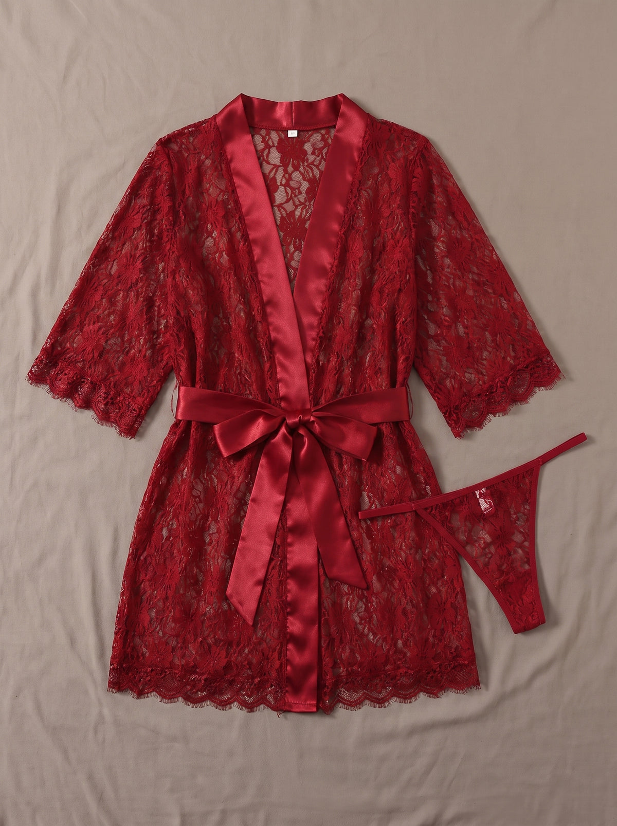 Ensemble kimono en dentelle rouge transparente et string assorti posés à plat