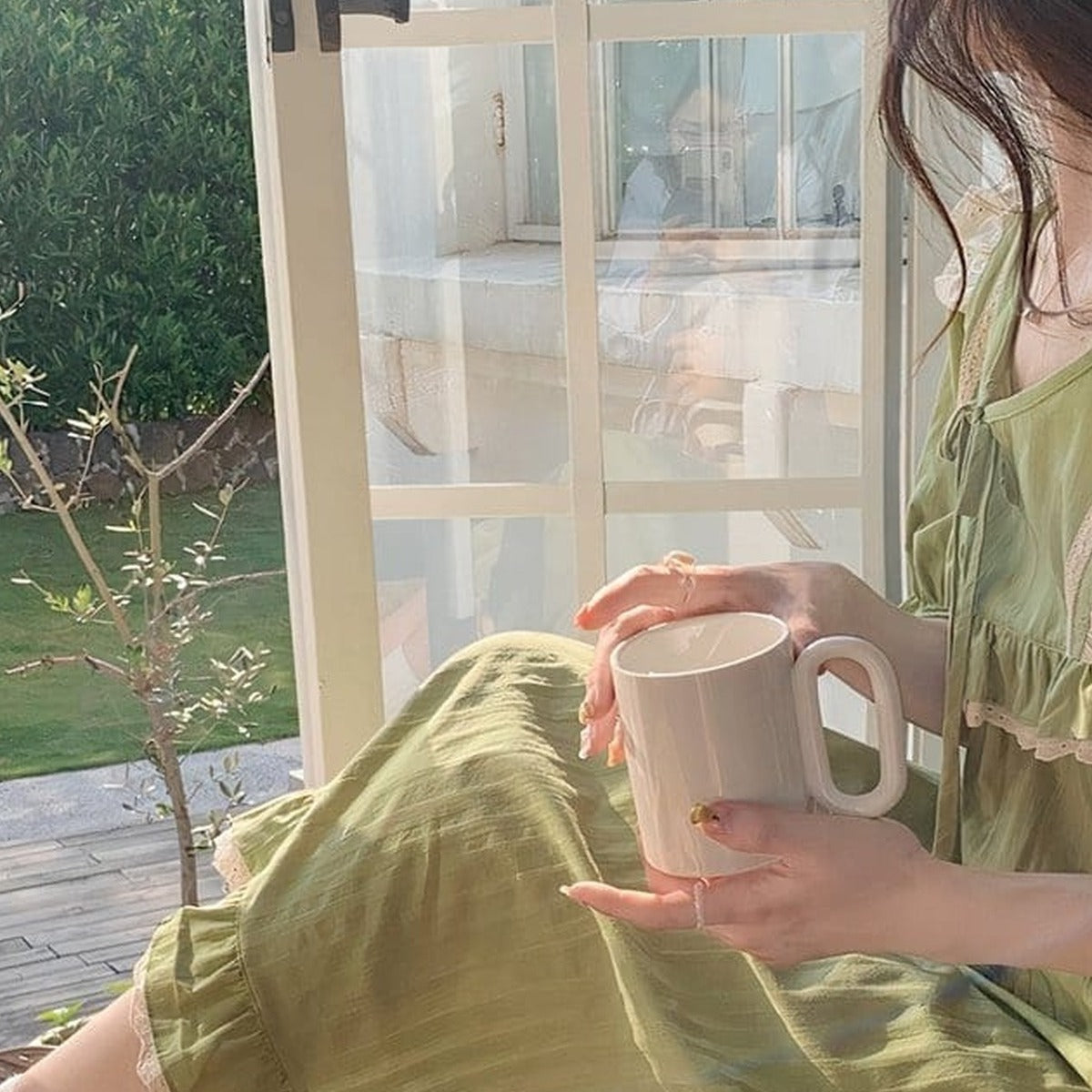 Modele de profil tenant une tasse, lumiere du matin sur la nuisette verte en coton