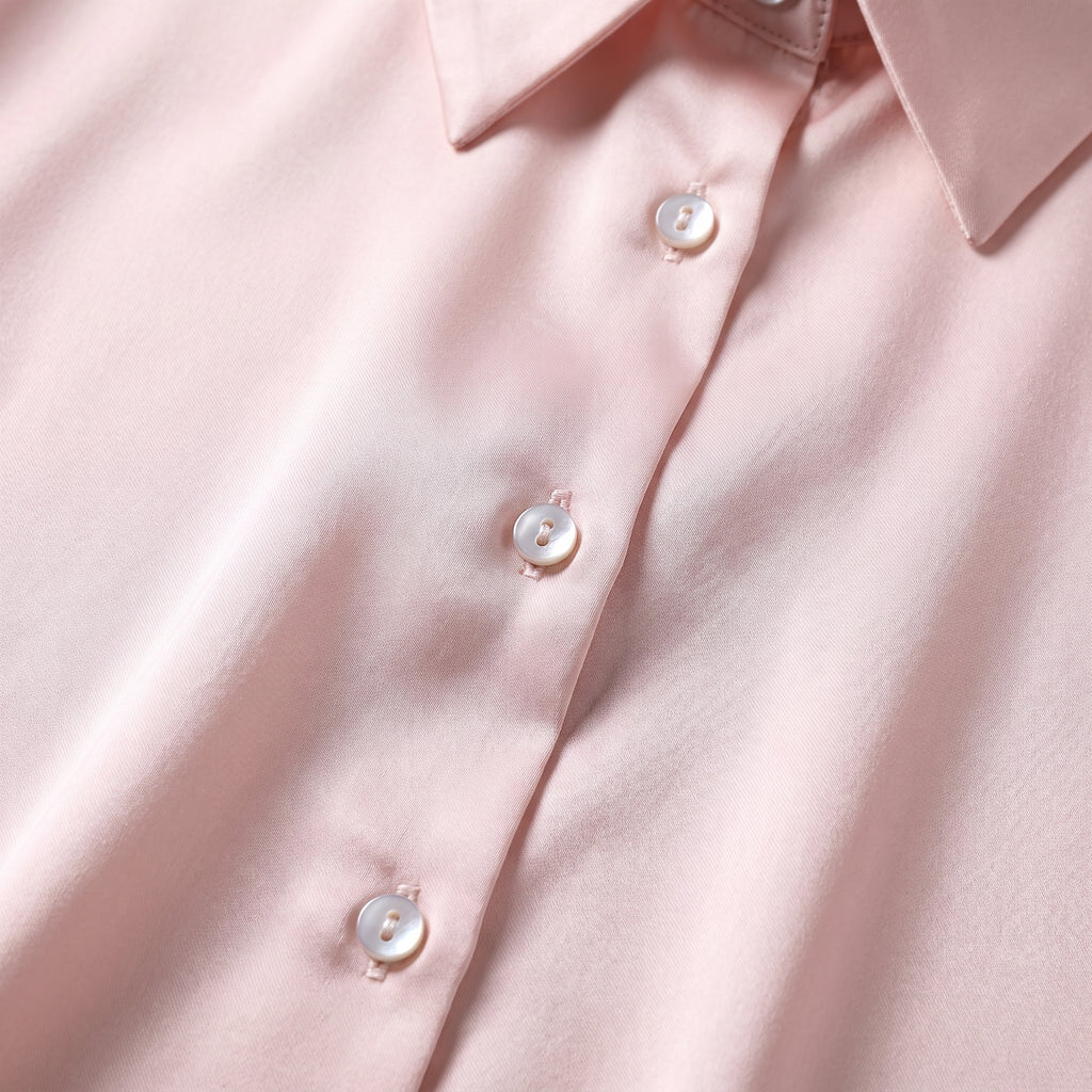 Détail des boutons nacrés et du col chemise sur le satin rose poudré