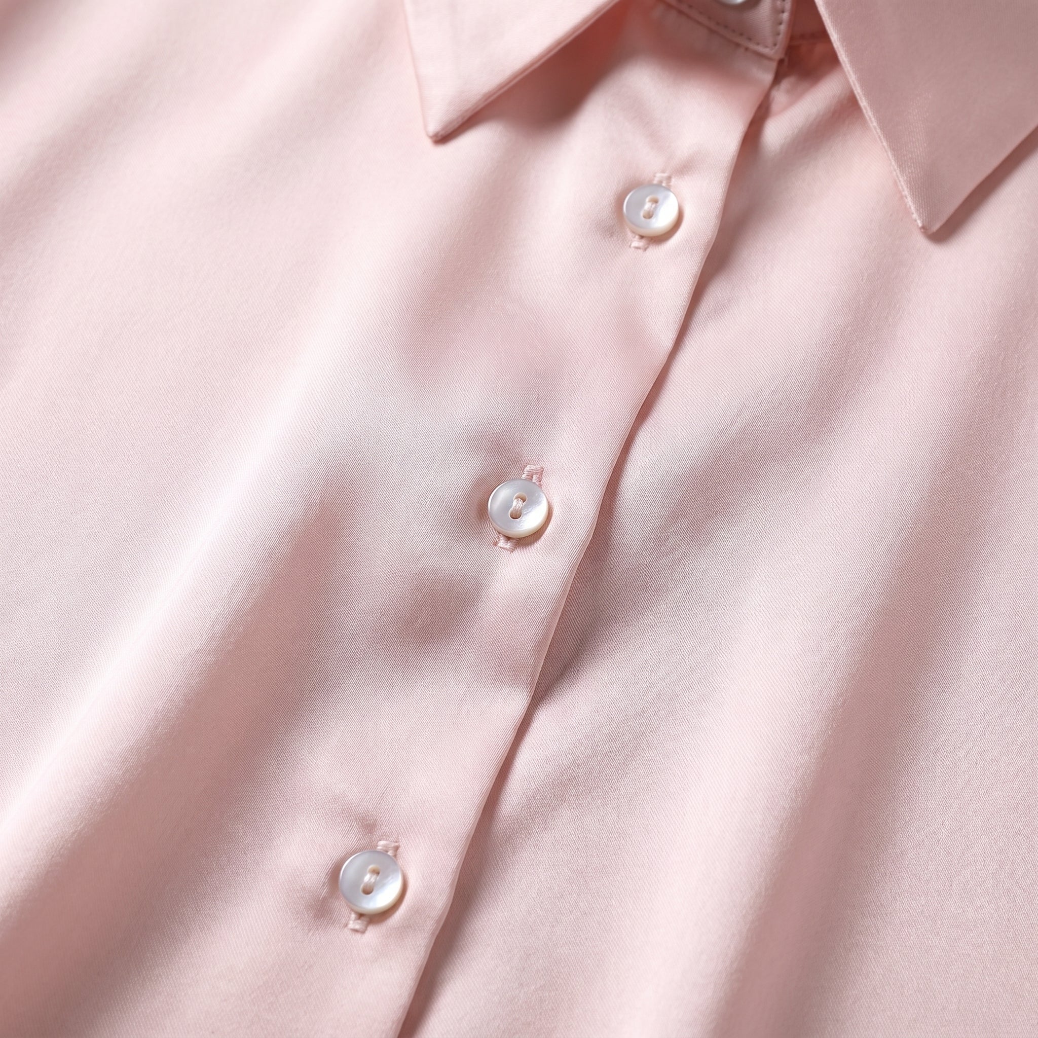 Détail des boutons nacrés et du col chemise sur le satin rose poudré Image