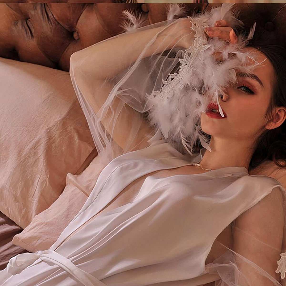 Visage et décolleté plongeant de la nuisette en satin, plumes blanches aux poignets