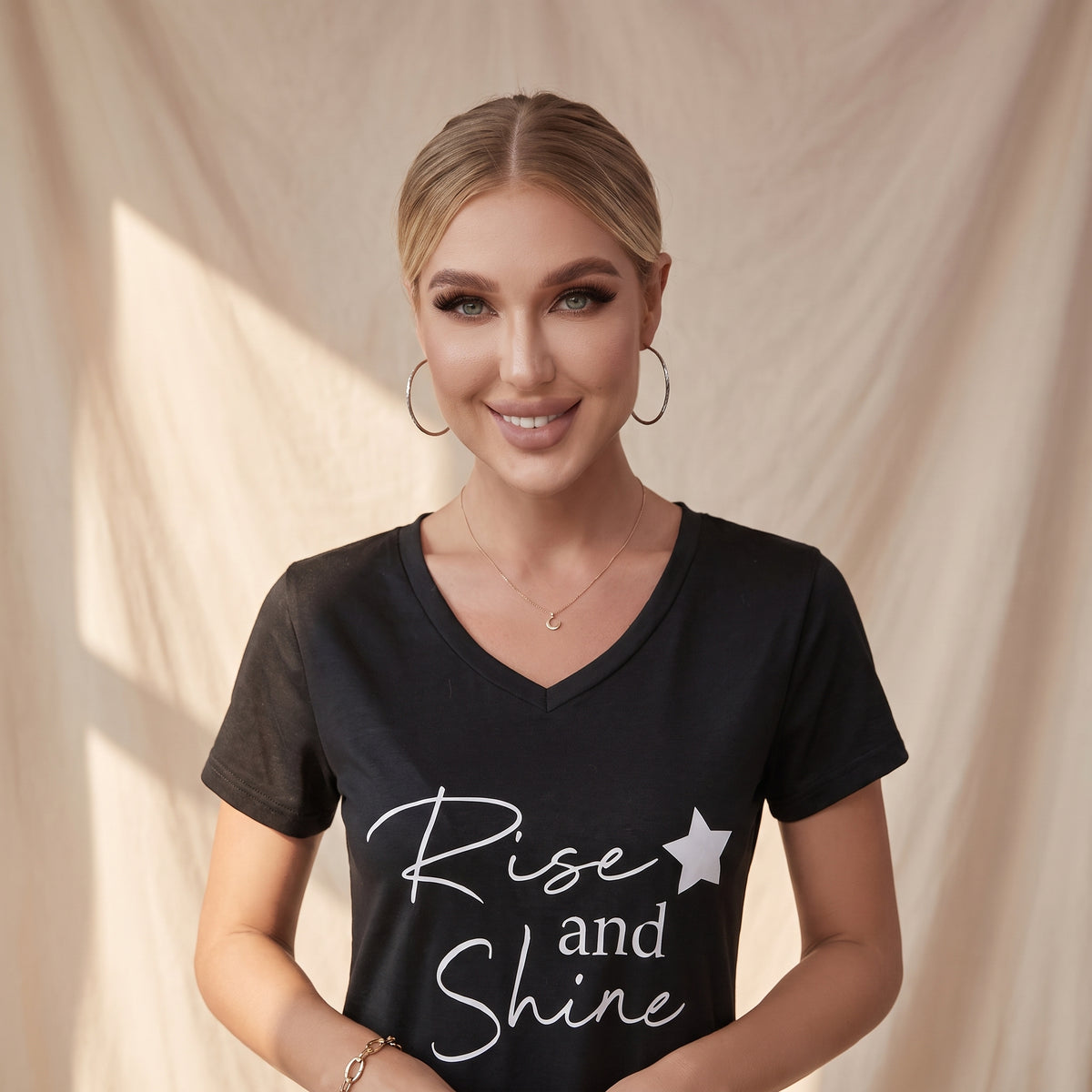 Portrait du modele portant la nuisette noire message Rise and Shine, chignon et bijoux dores