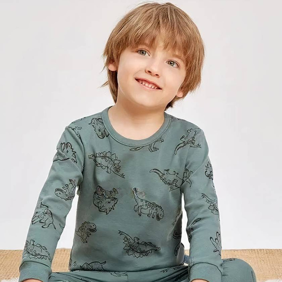 Portrait souriant d'un garcon en pyjama dinosaures vert Image