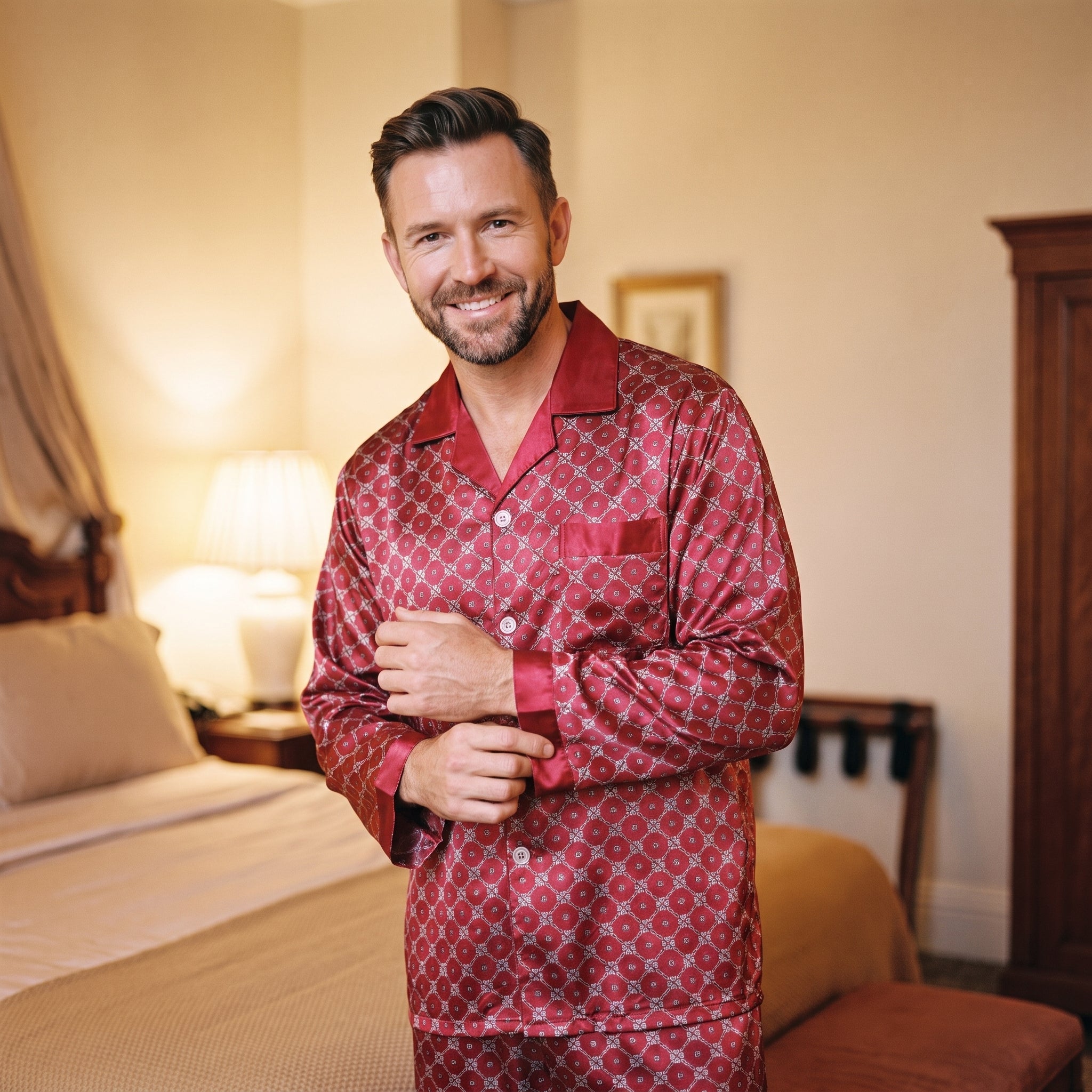 Homme debout dans sa chambre en fin de journée, il ajuste le poignet de sa chemise de pyjama satiné rouge, les boutons fermés Image