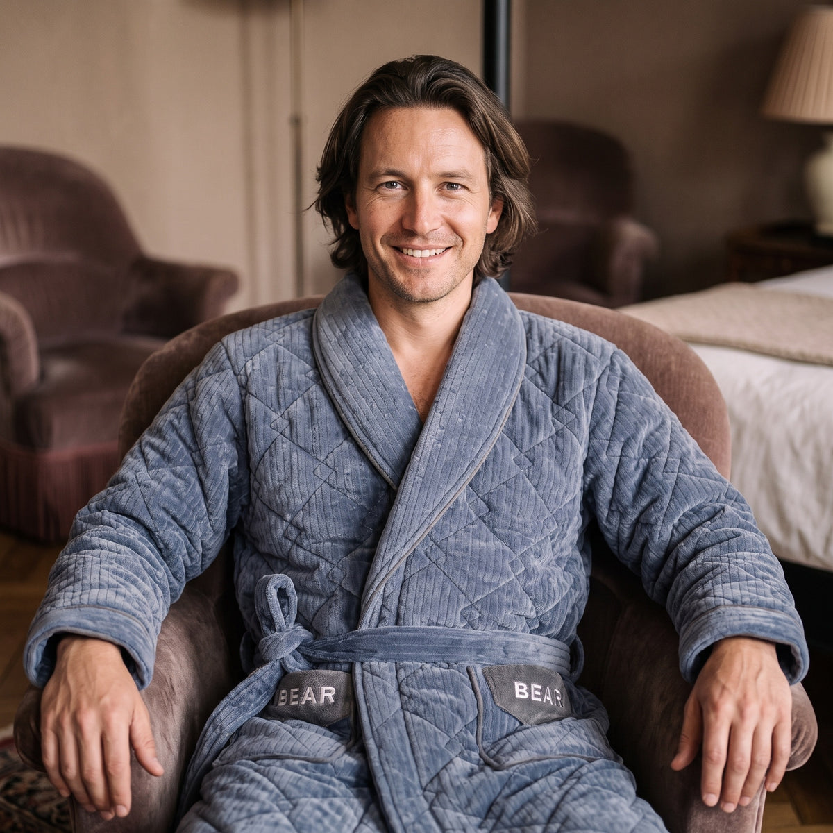 Homme souriant dans le peignoir polaire bleu avec ceinture nouée