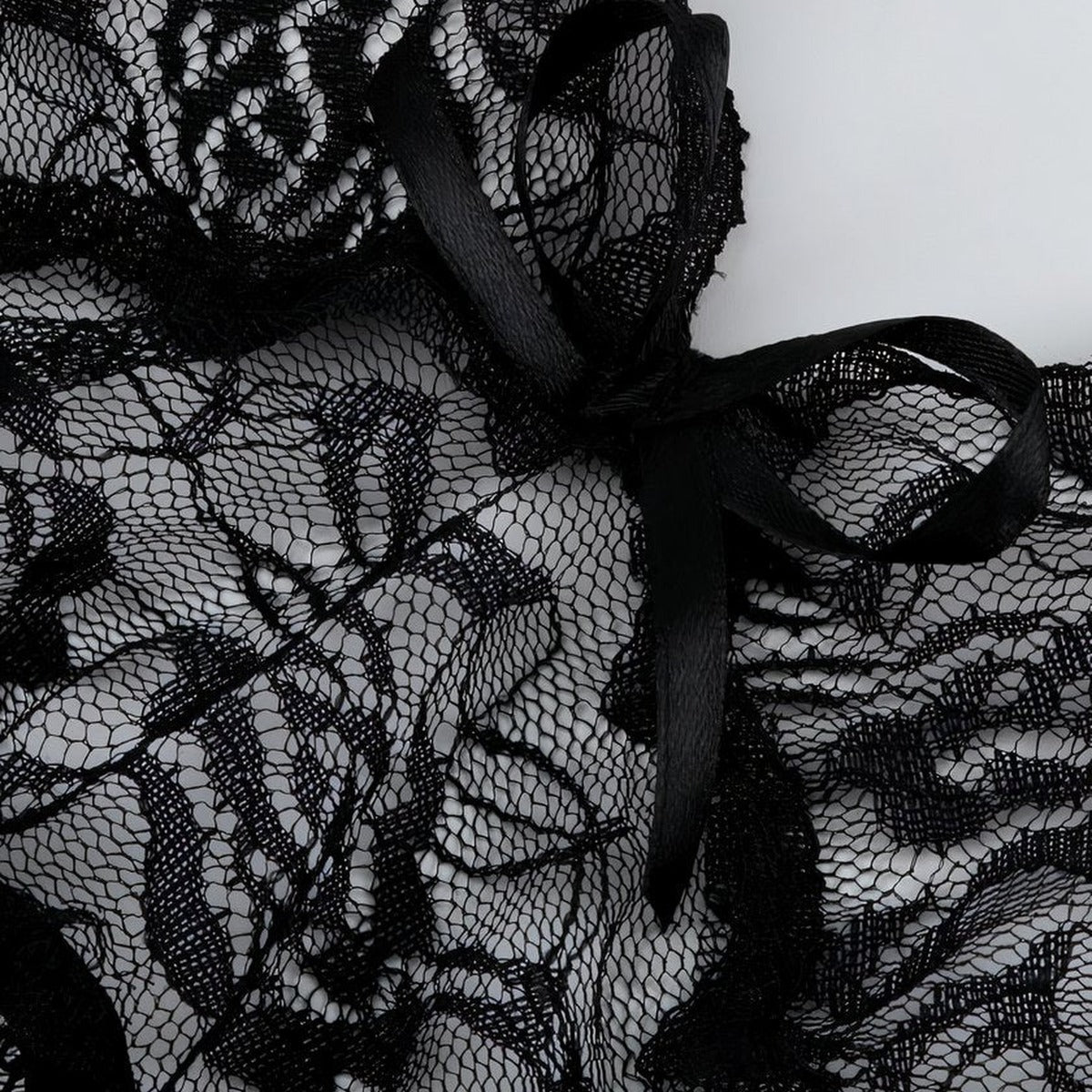 Gros plan sur la dentelle florale et le noeud satine de la nuisette noire, le detail qui capte la lumiere et attire le regard Image