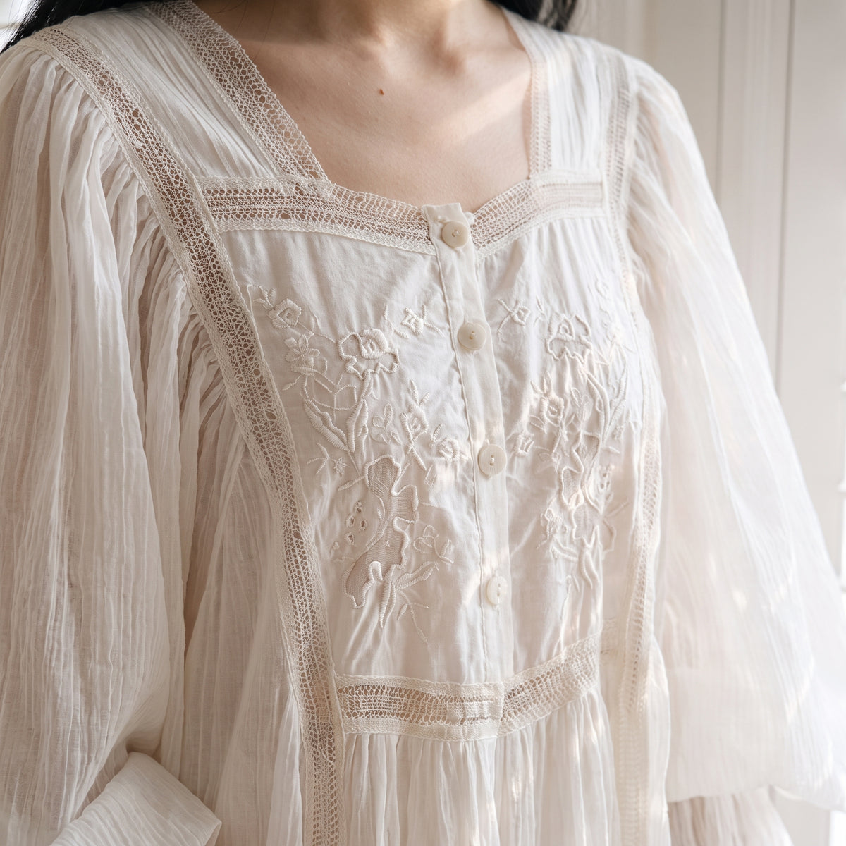 Détail du plastron brodé, des boutons et du col en dentelle