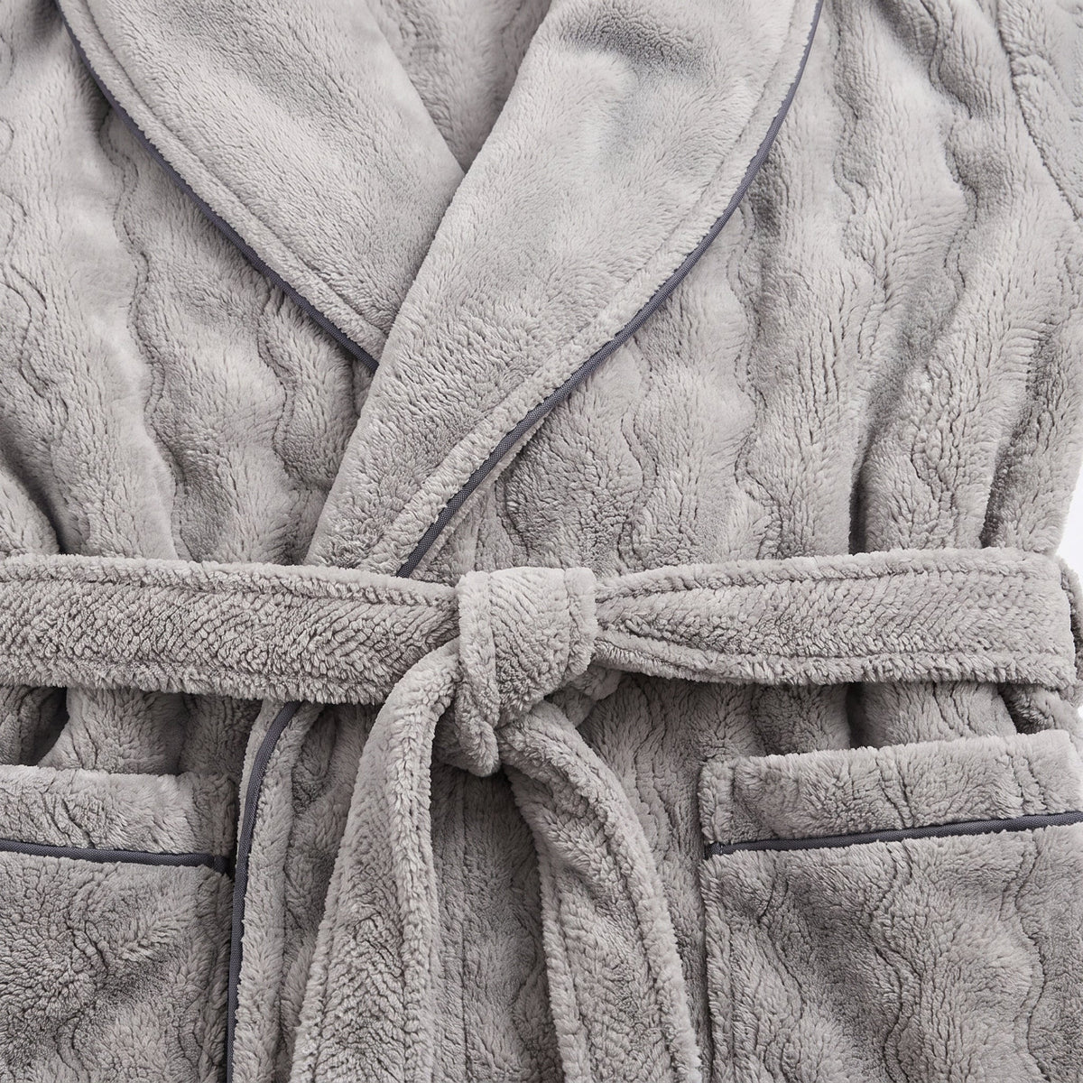 Gros plan sur le nœud de ceinture d'un peignoir polaire gris, le relief en vagues de l'étoffe et le liseré foncé au bord du col
