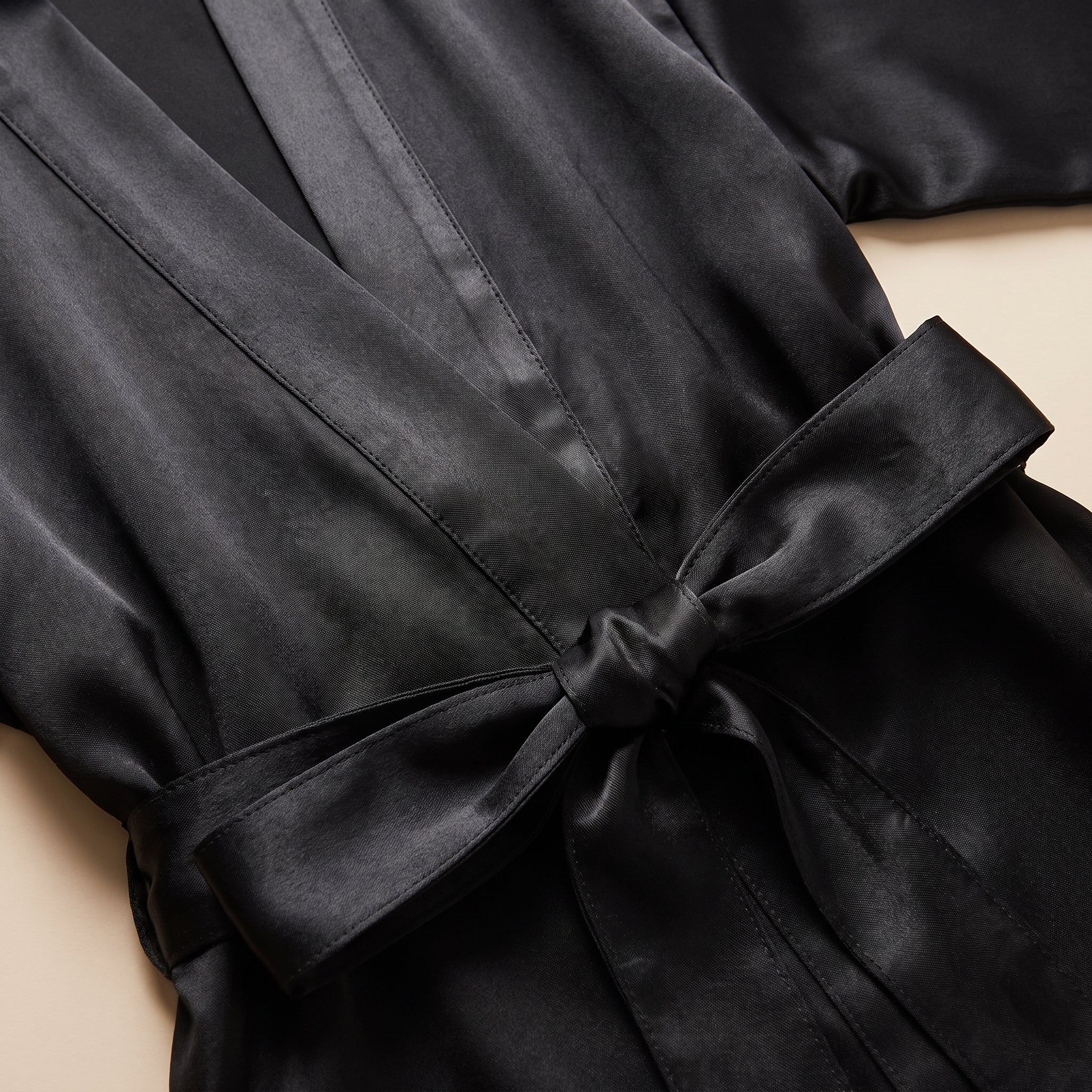 Détail du col châle croisé et du noeud de ceinture en satin noir Image