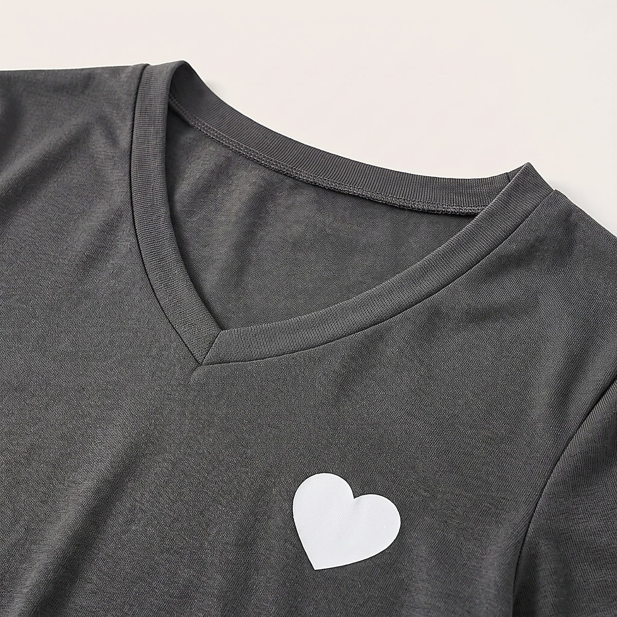 Détail du col en V et du petit coeur blanc imprimé sur le jersey gris