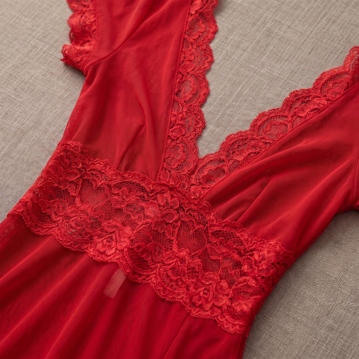 Détail du décolleté en V bordé de dentelle rouge et de la ceinture de dentelle