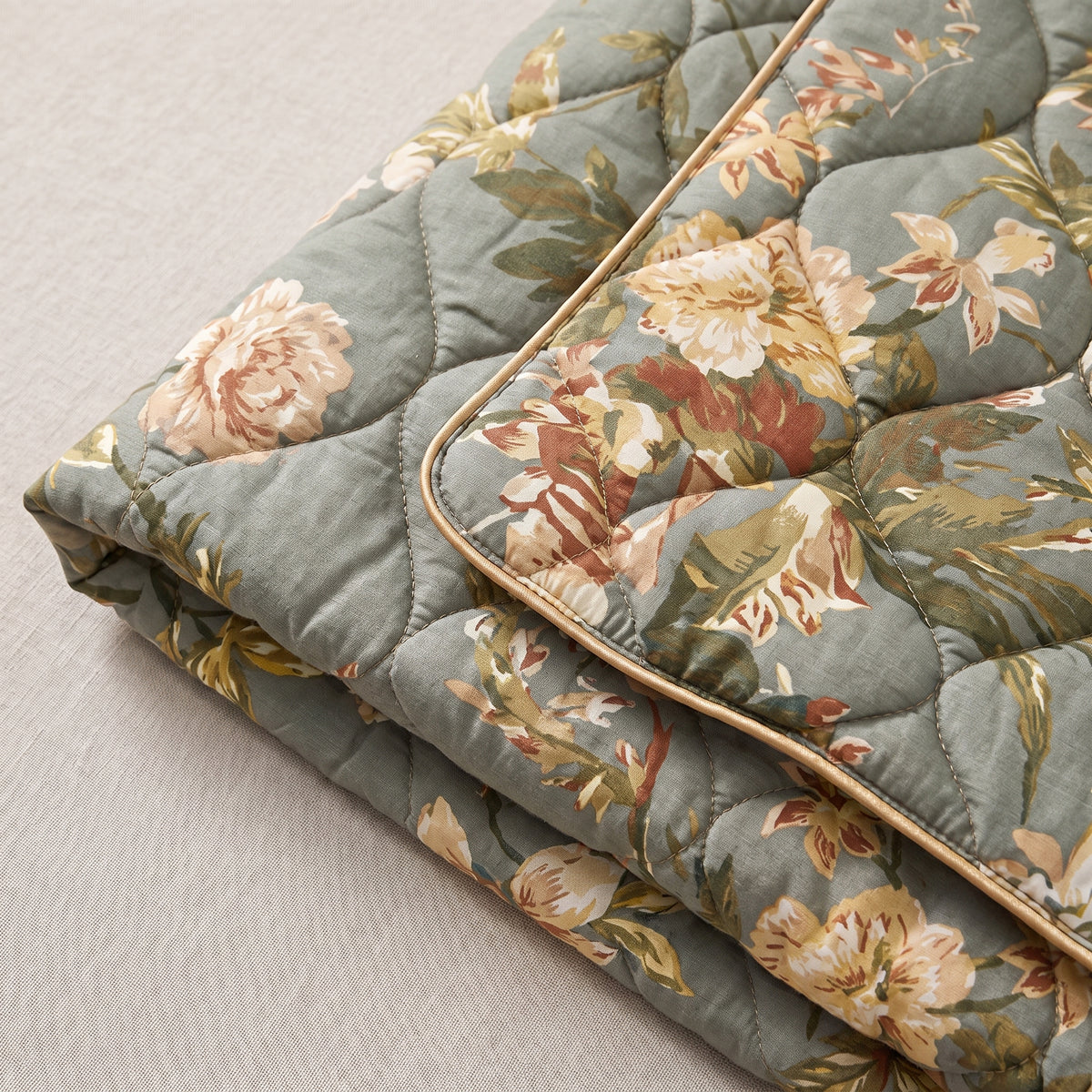 Détail du col châle à liseré doré et de l'imprimé floral du tissu matelassé