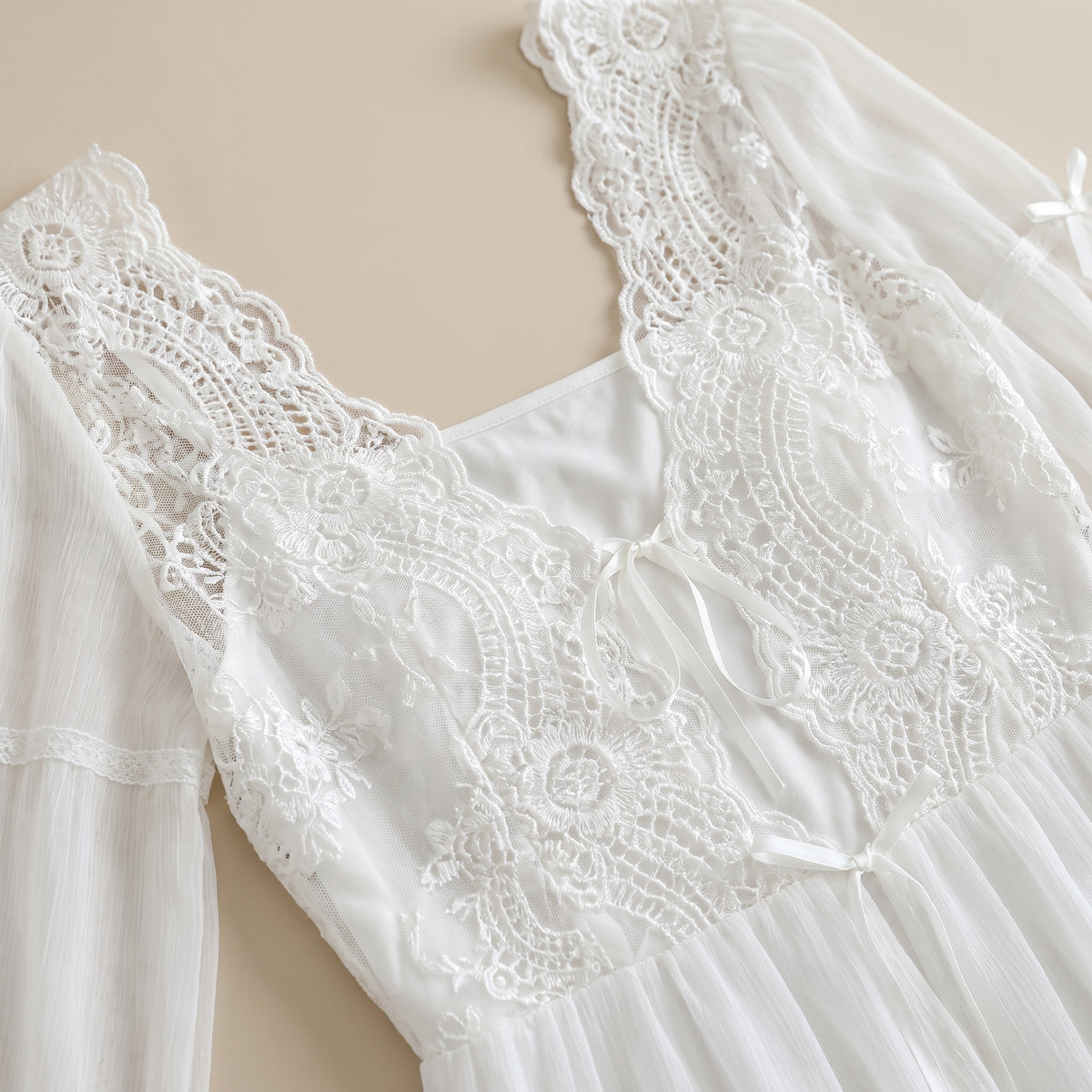 Détail du buste en dentelle blanche brodée et des rubans noués
