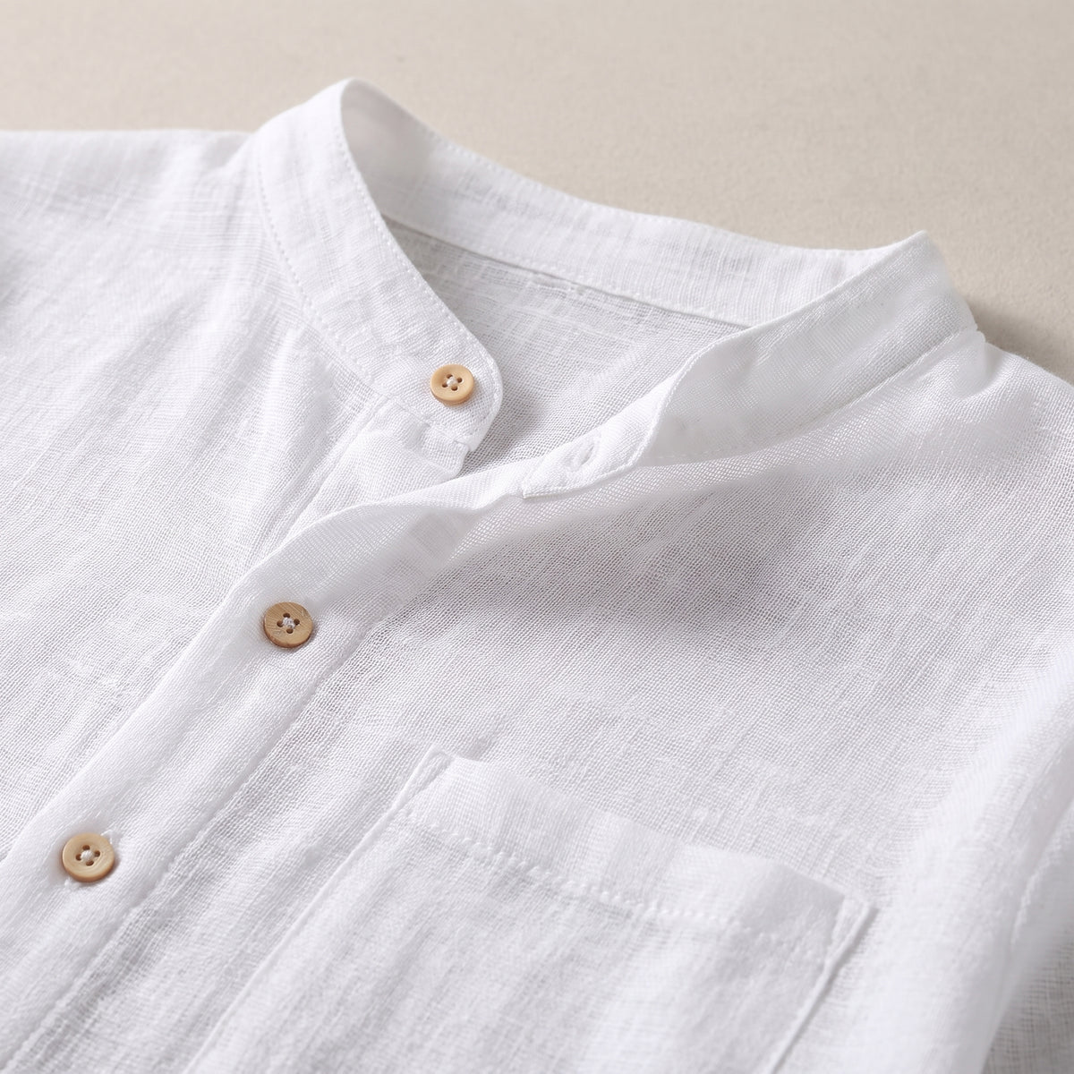 Détail du col rond boutonné et de la poche de la chemise de nuit blanche