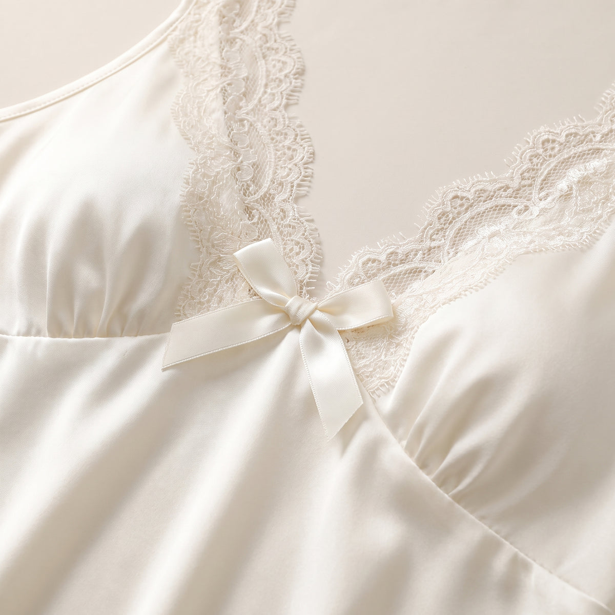 Détail du décolleté en V en dentelle et du noeud de la nuisette satin