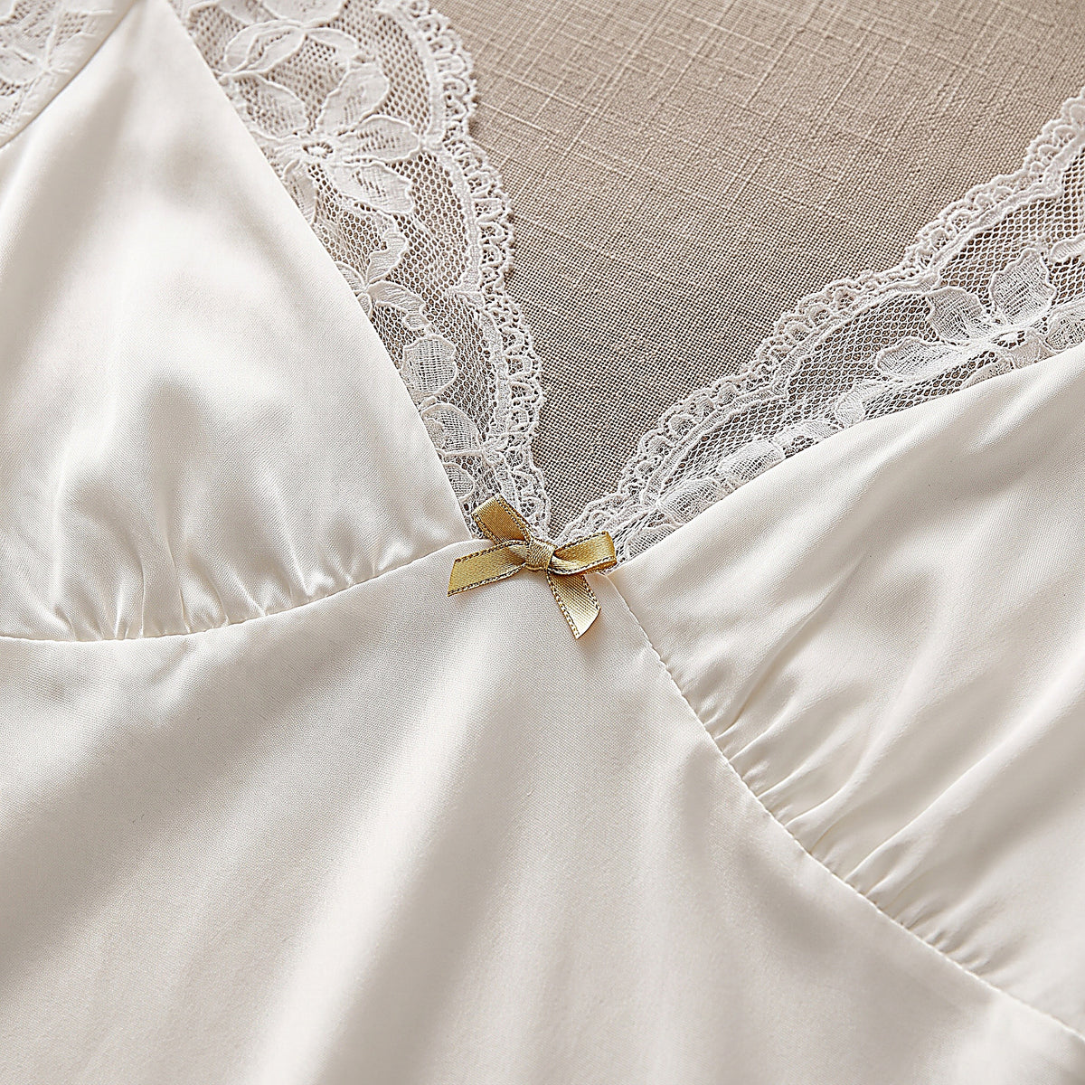 Détail du décolleté en V en dentelle et du petit noeud doré