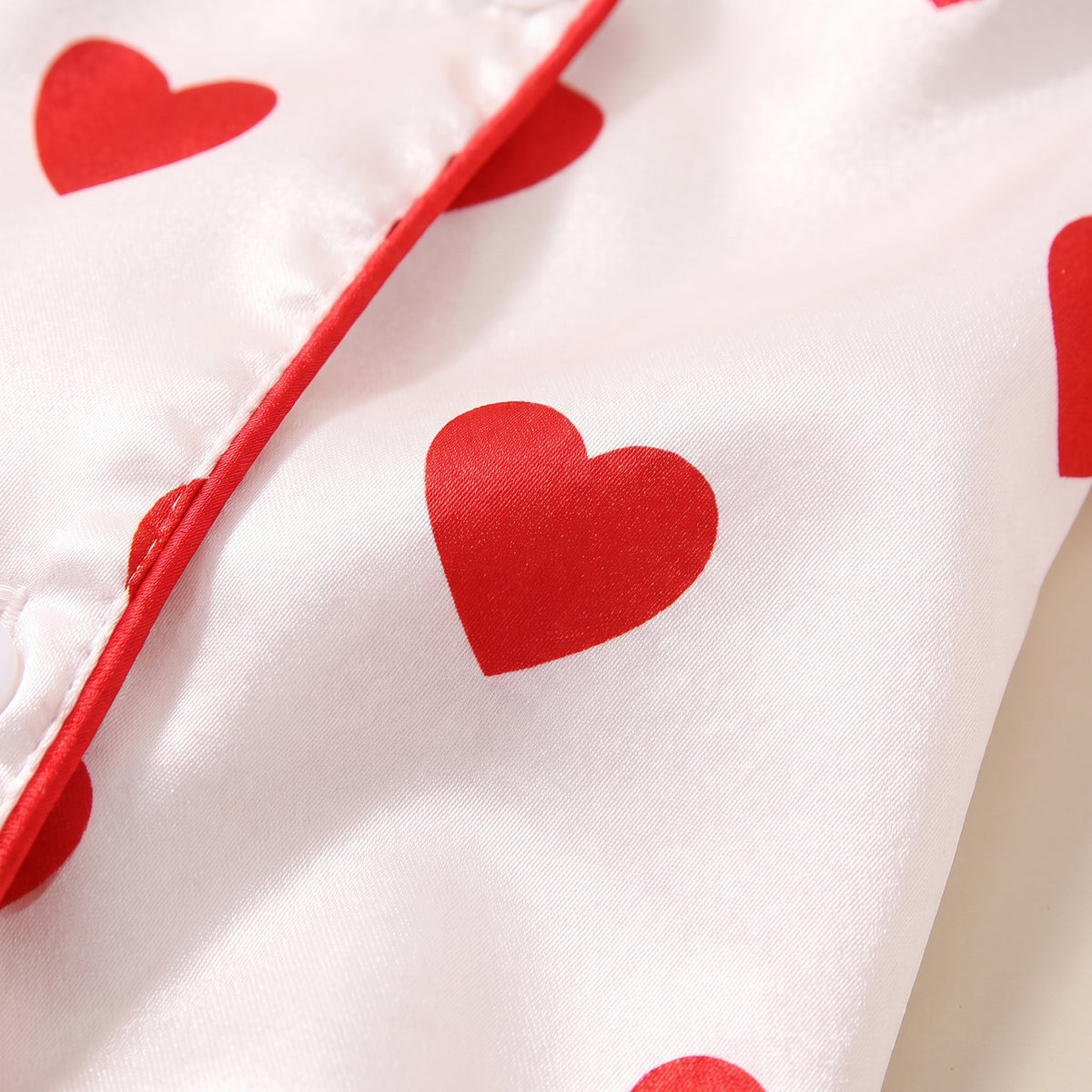 Gros plan sur le satin, un coeur rouge et le passepoil du boutonnage Image