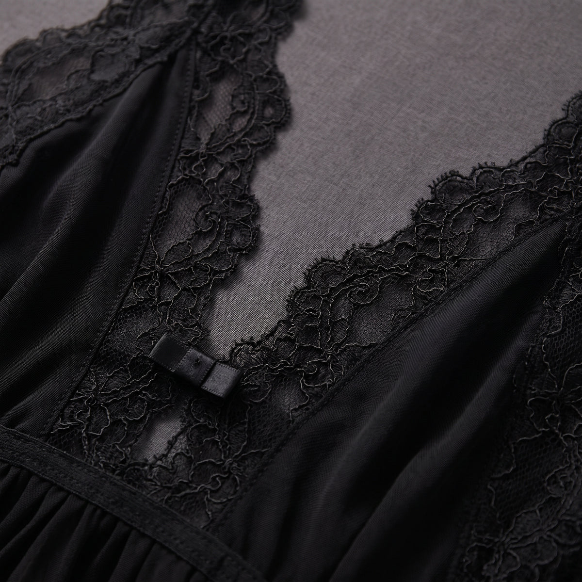 Détail de la dentelle festonnée noire et du petit noeud du décolleté