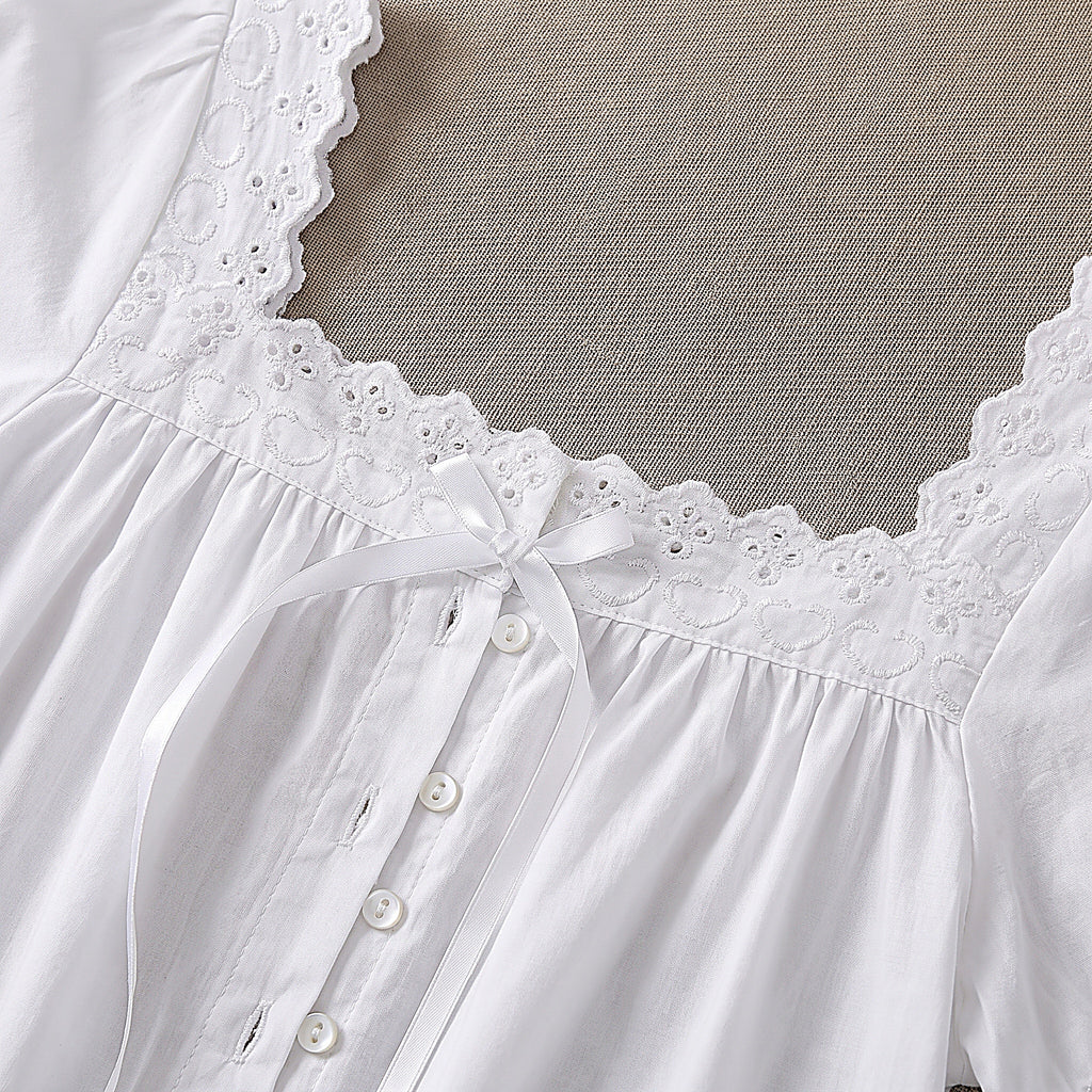 Détail du col carré bordé de dentelle, du petit noeud satin et du boutonnage