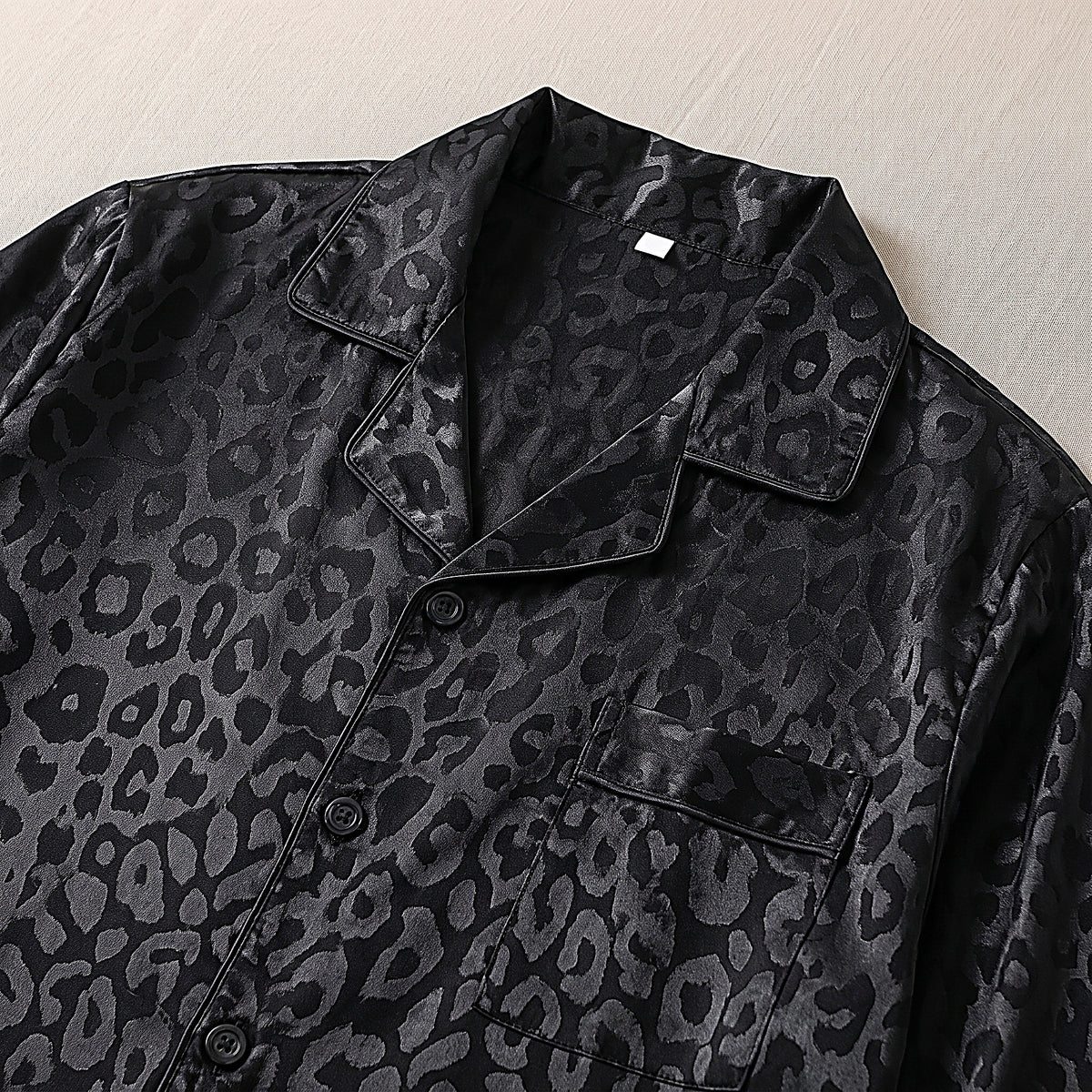 Détail du col cranté et du fin liseré de la chemise de pyjama en satin noir