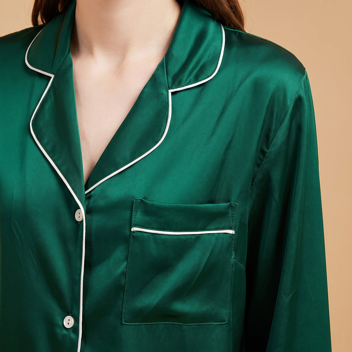 Détail du col tailleur et de la poche bordés de passepoil blanc, satin vert