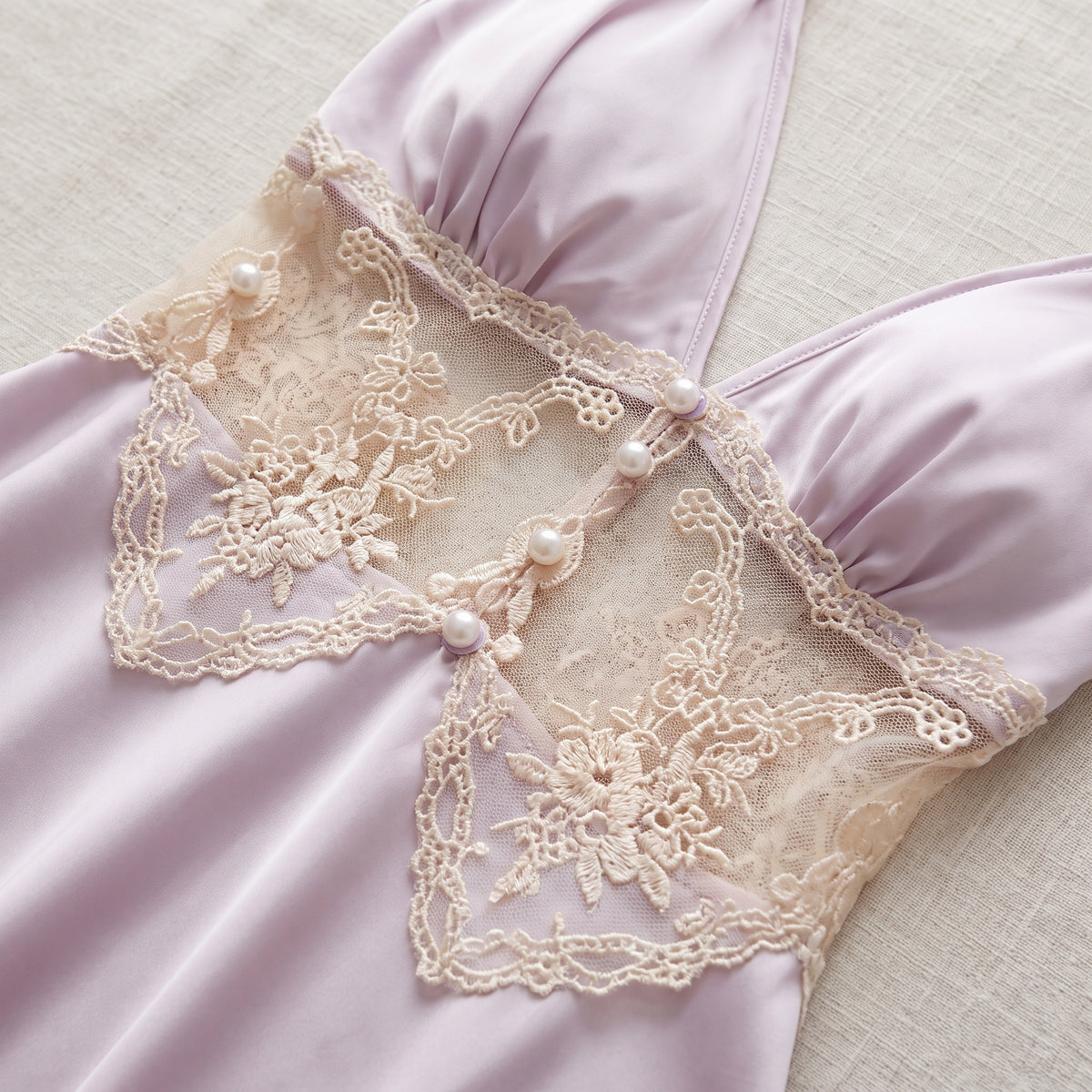 Détail de l'empiècement en dentelle crème et des perles à la taille