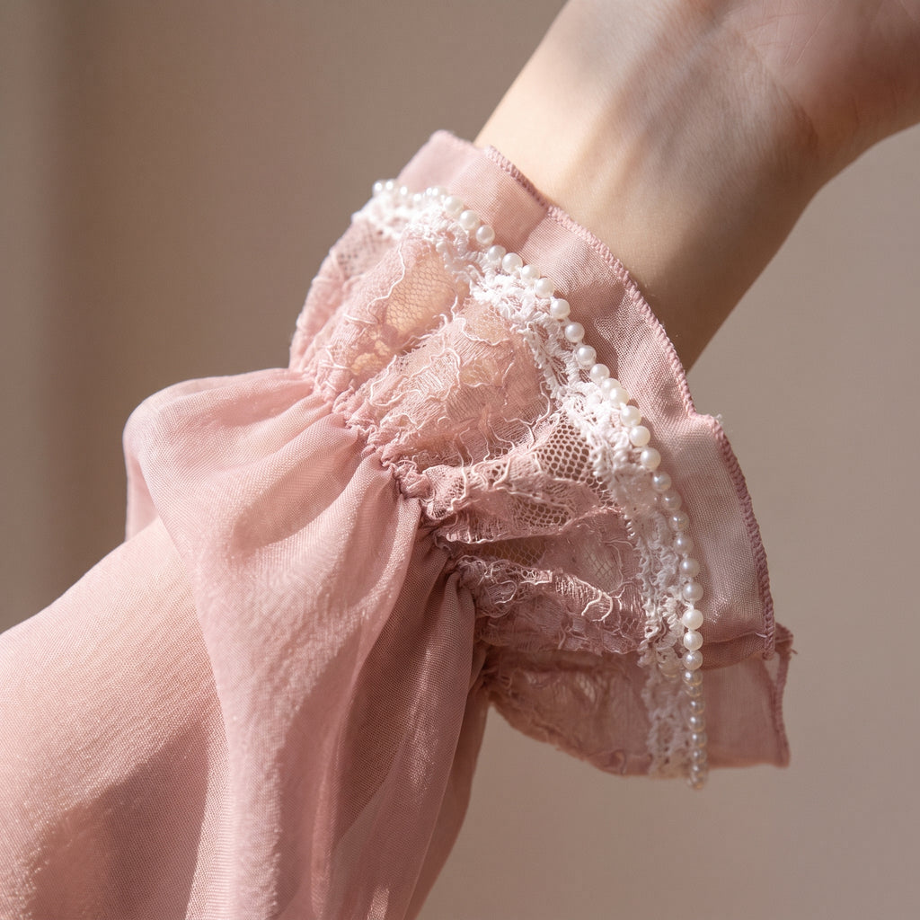 Manche ample et poignet volanté du kimono en voile rose, bordé de dentelle et de perles