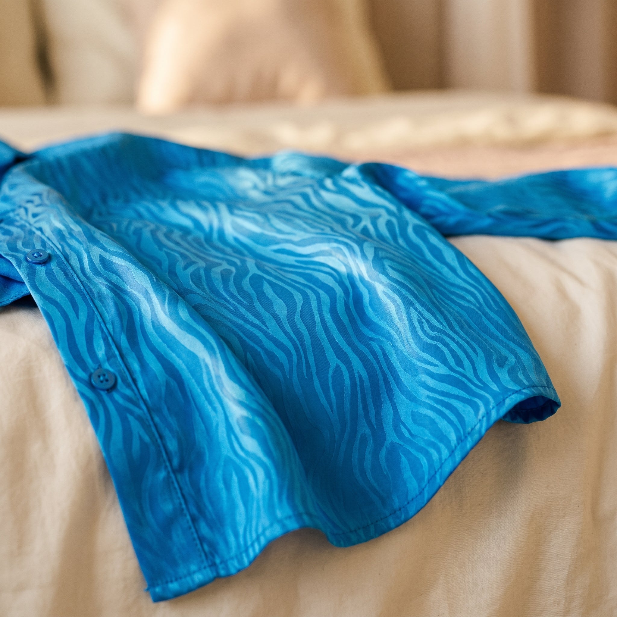 Gros plan sur le satin bleu du pyjama, ses ondulations ton sur ton et deux boutons de la même couleur que l'étoffe Image