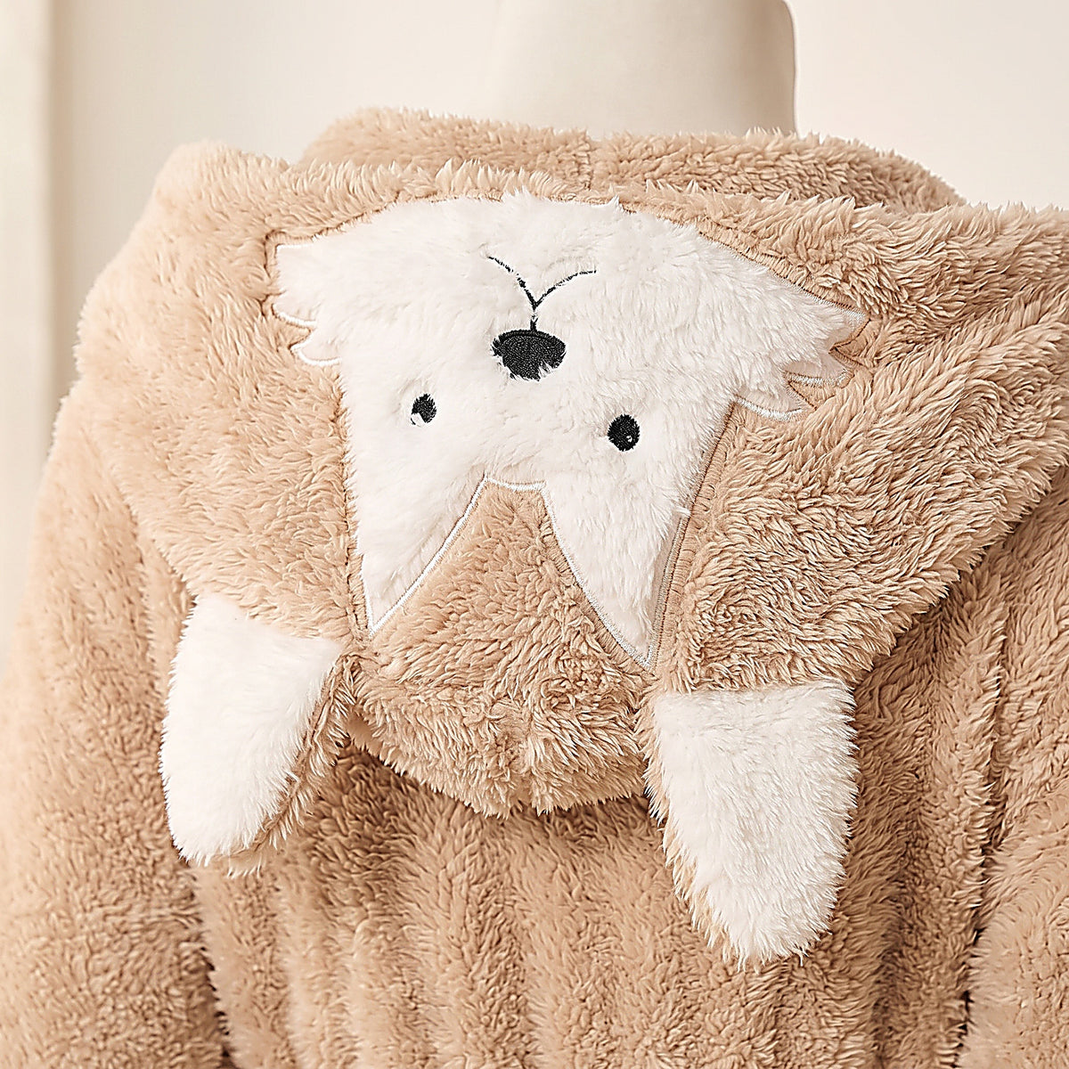 Détail du visage de chien blanc en peluche à l'arrière de la capuche
