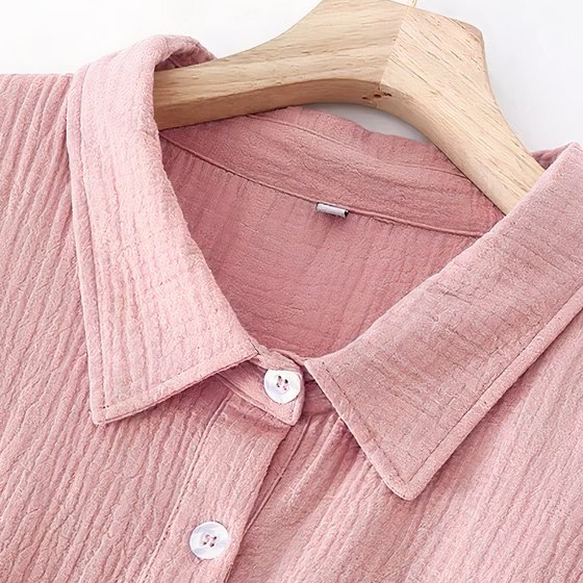 Col à revers à deux pointes et premiers boutons clairs d'une robe de chambre rose suspendue à un cintre
