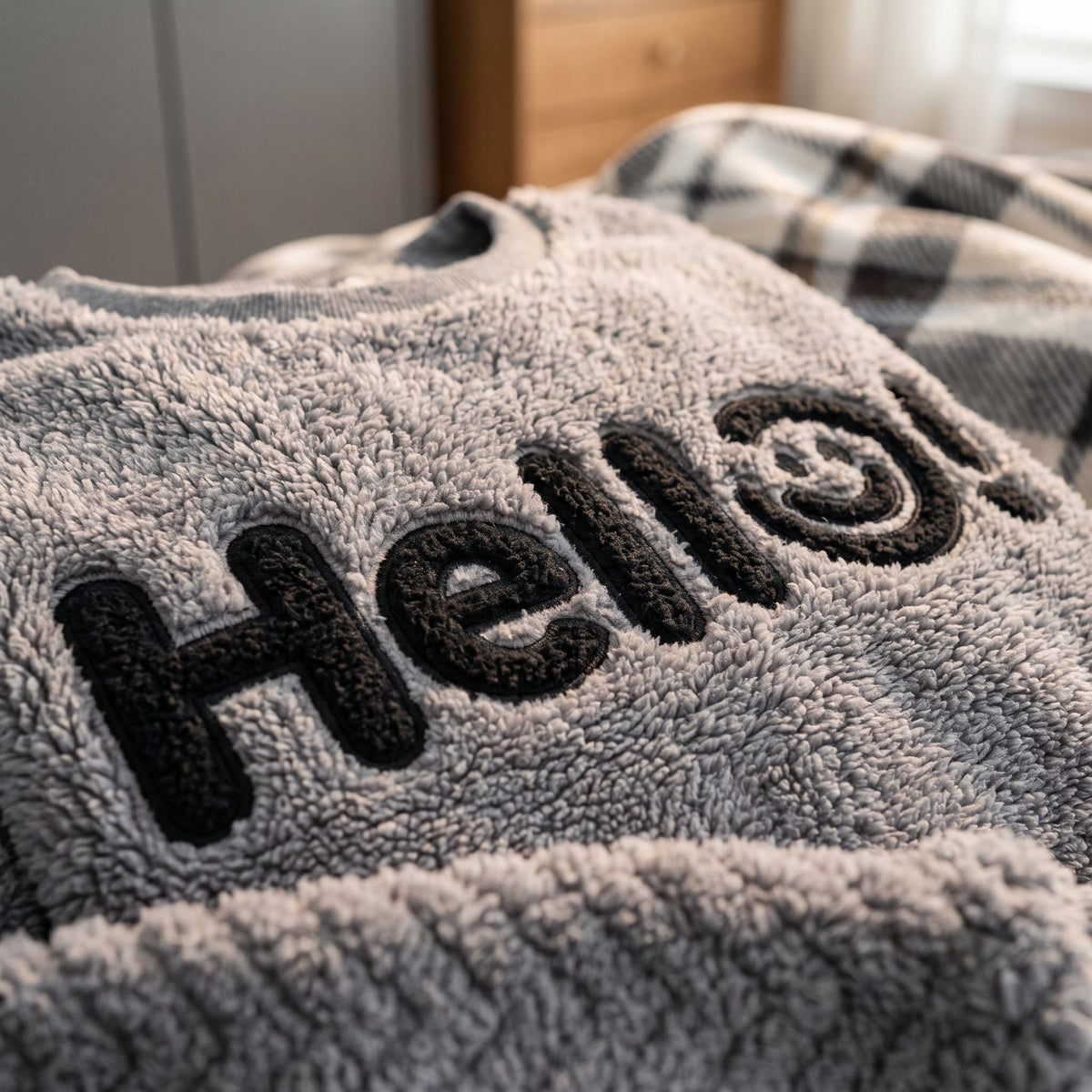 Gros plan sur le lettrage Hello brodé en relief et la maille polaire moelleuse du pyjama