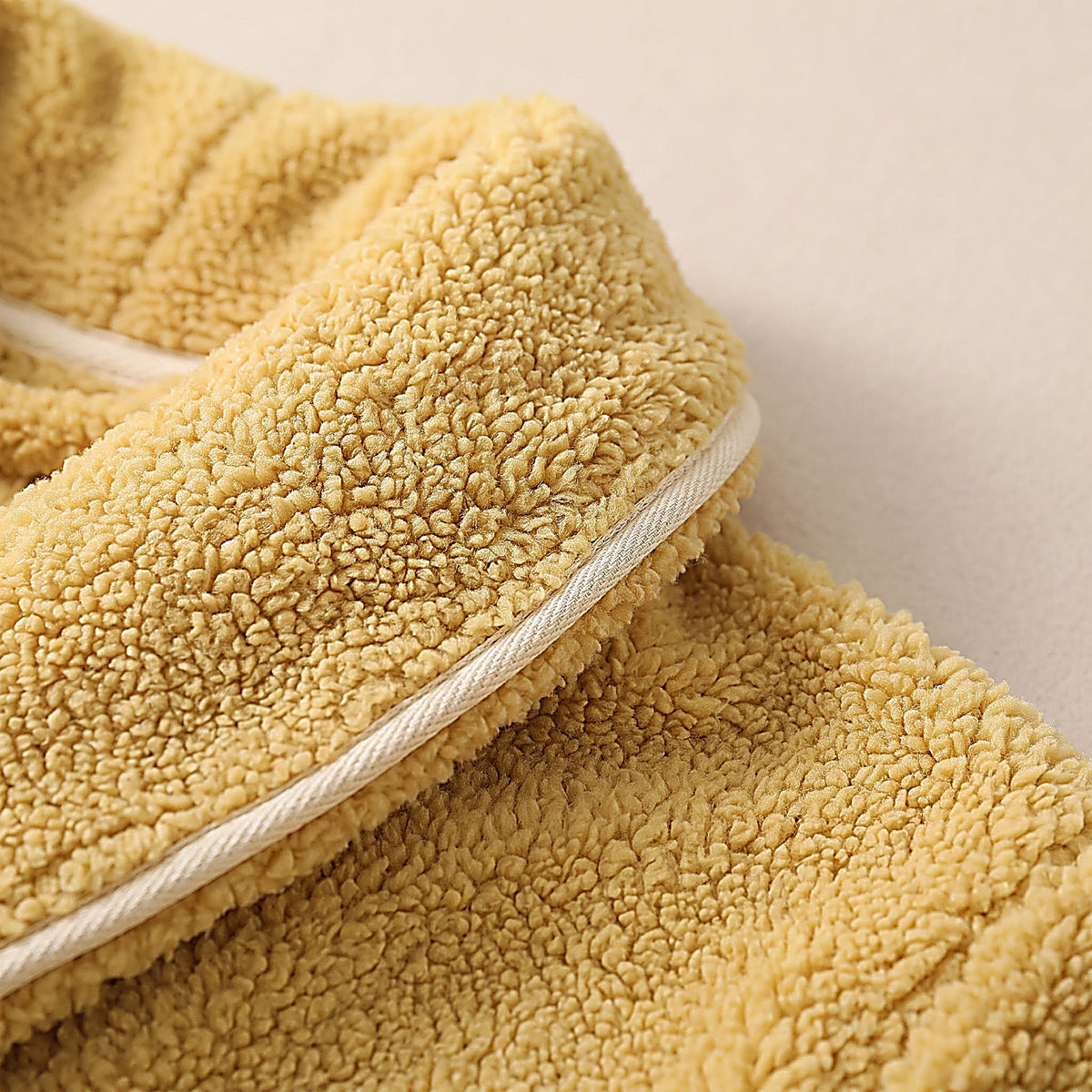 Détail du col châle à passepoil crème et de la texture bouclée jaune moutarde