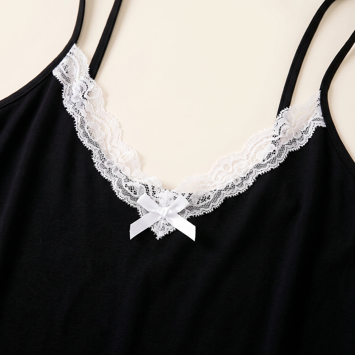 Détail du décolleté en V bordé de dentelle blanche et du noeud satin